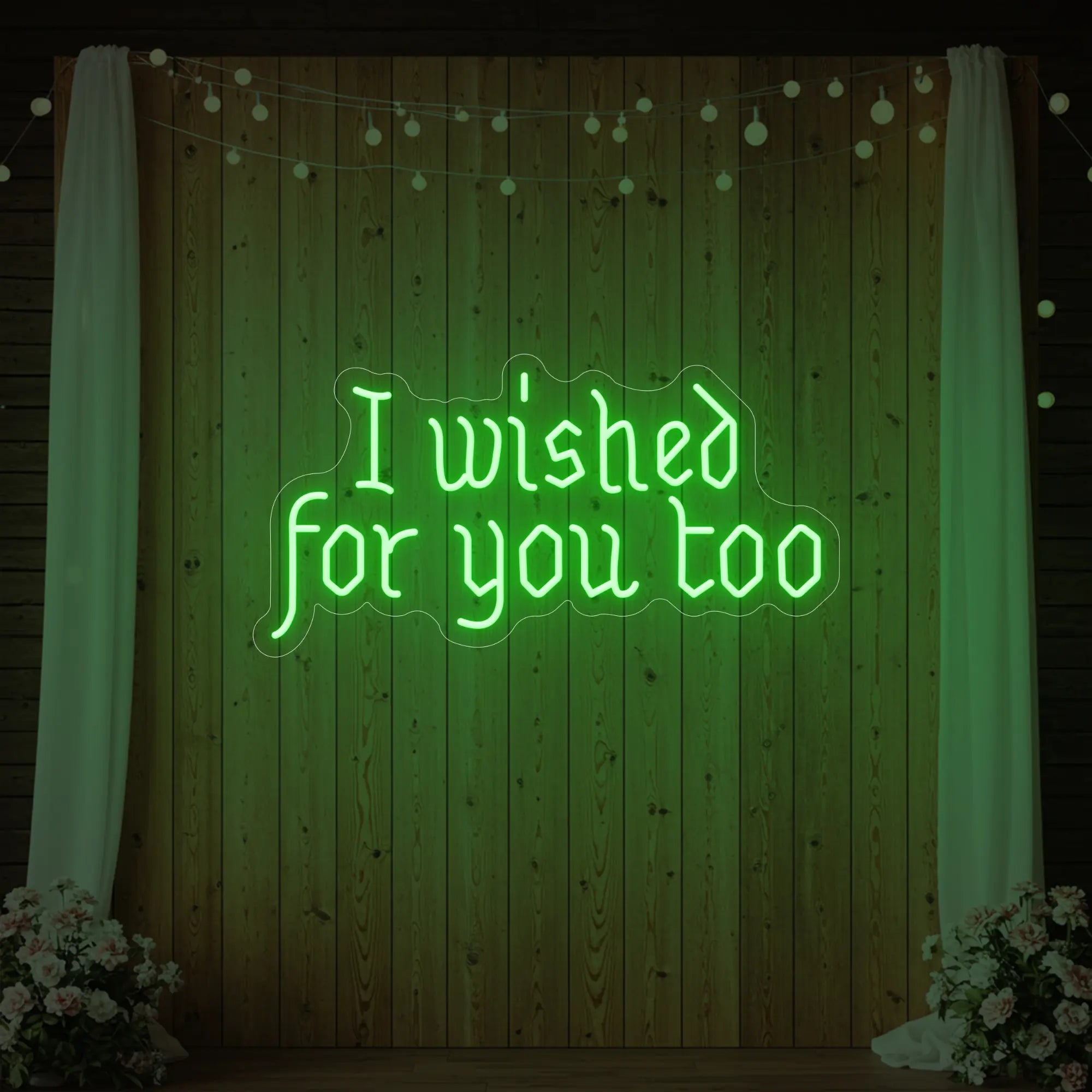 Photo of the 'I Wished For You Too' neon sign glowing in green against a styled interior wall.