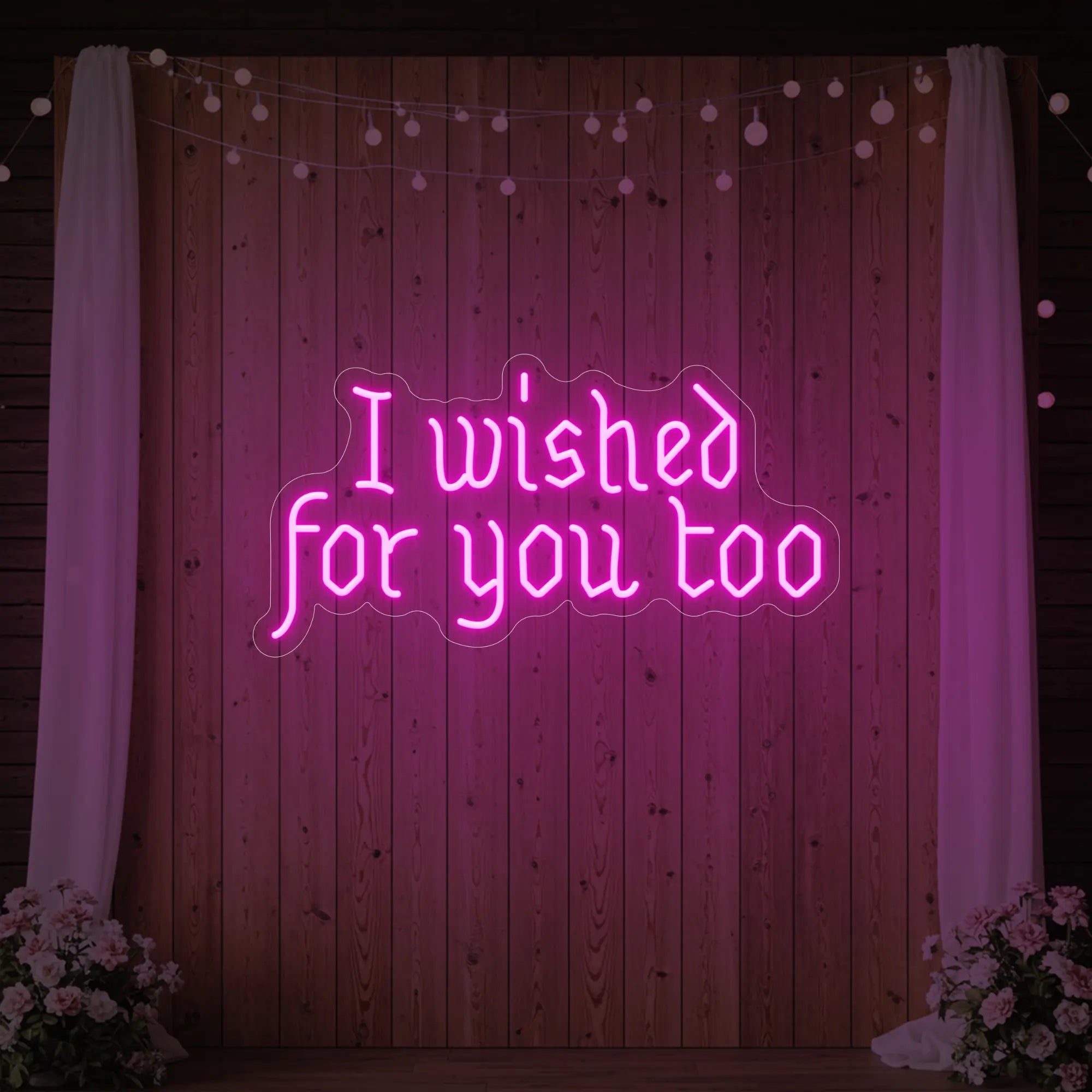 Photo of the 'I Wished For You Too' neon sign glowing in light pink against a styled interior wall.
