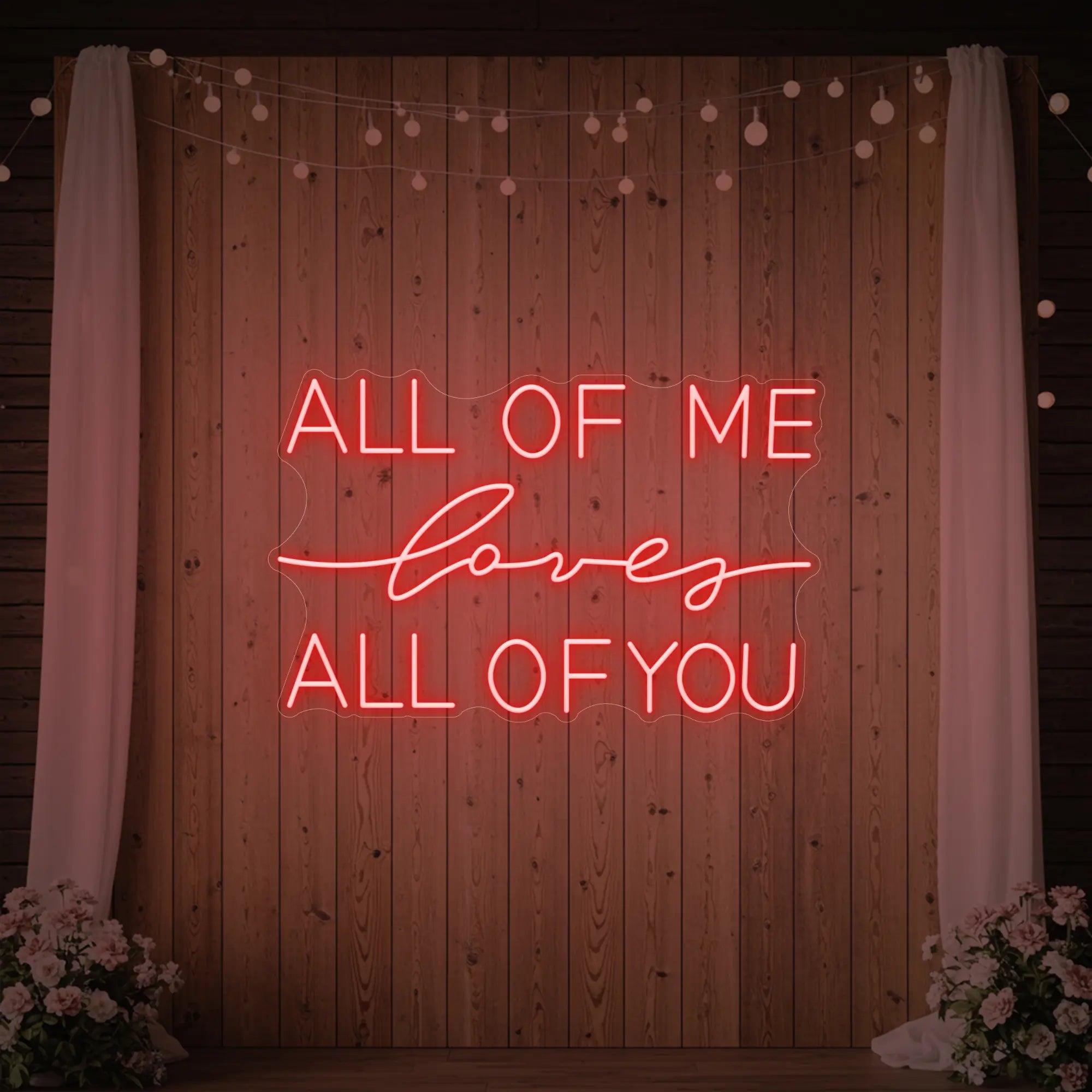Photo of the 'All Of Me Love All Of You' neon sign glowing in red against a styled interior wall.