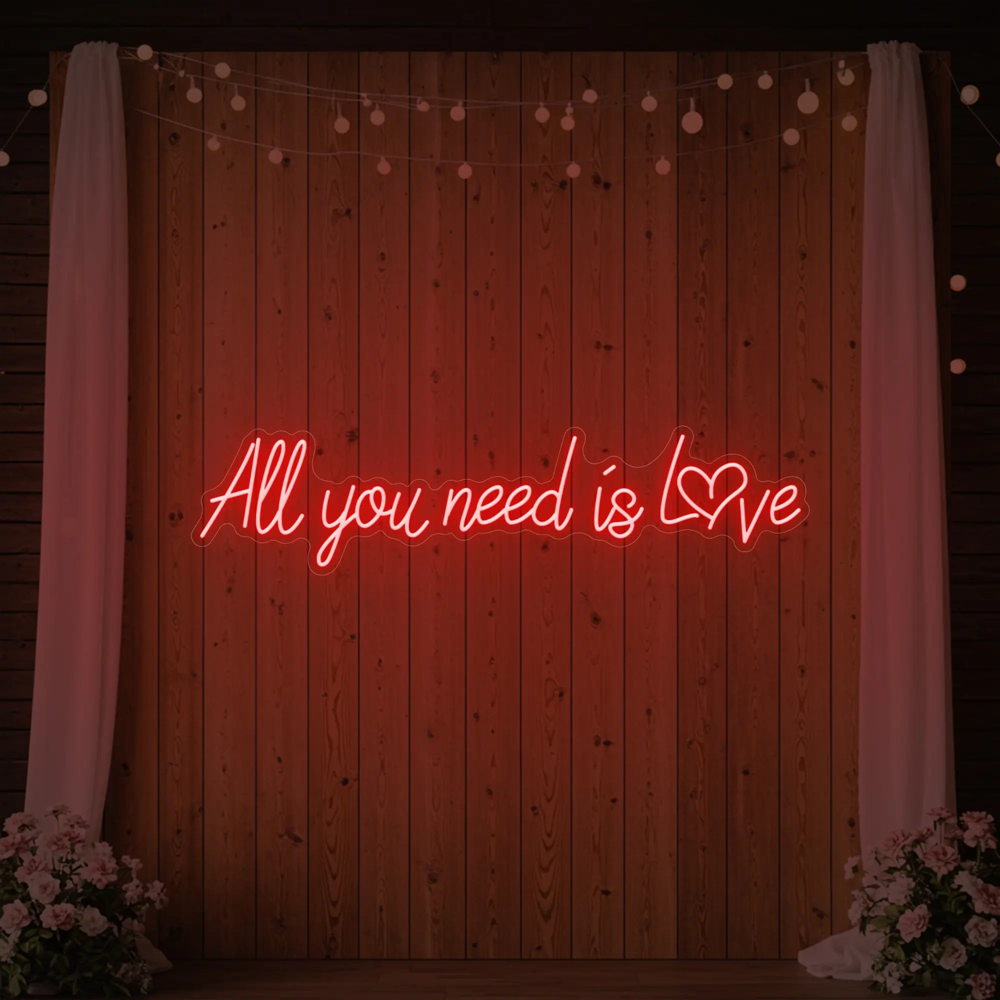 Photo of the 'All You Need Is Love Heart' neon sign glowing in red against a styled interior wall.