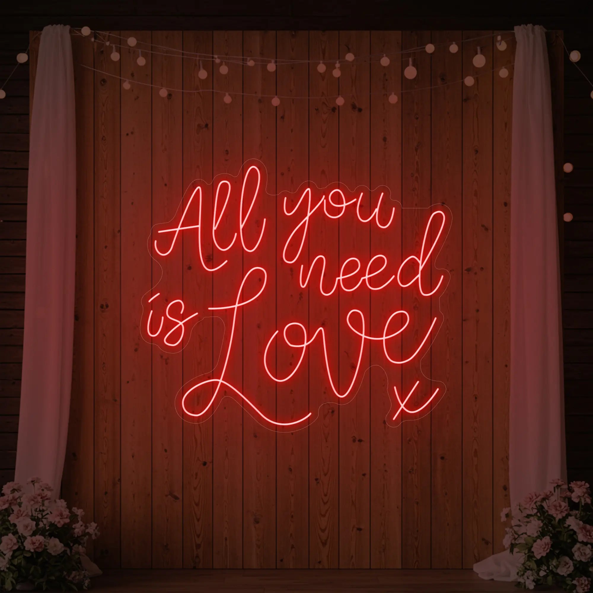 Photo of the 'All You Need Is Love V1' neon sign glowing in red against a styled interior wall.