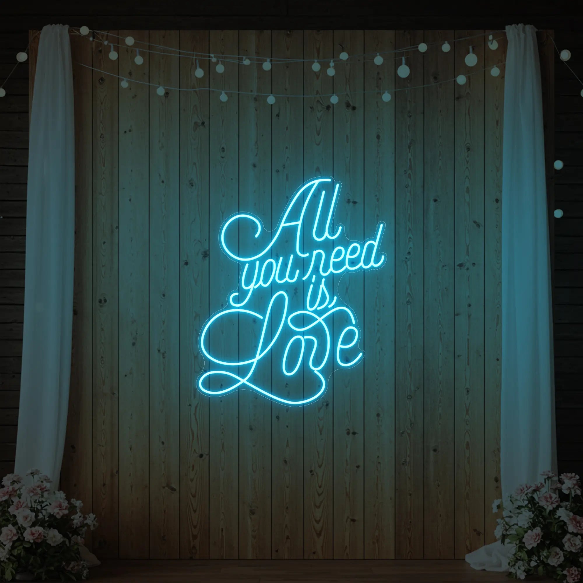 Photo of the 'All You Need Is Love V2' neon sign glowing in ice blue against a styled interior wall.