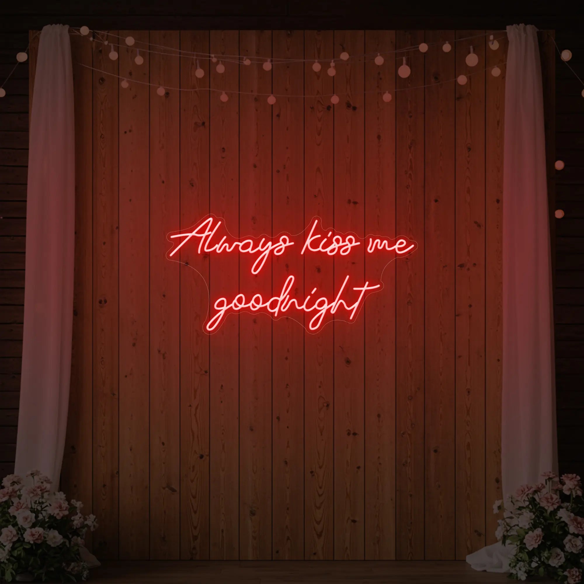 Photo of the 'Always Kiss Me Goodnight' neon sign glowing in red against a styled interior wall.