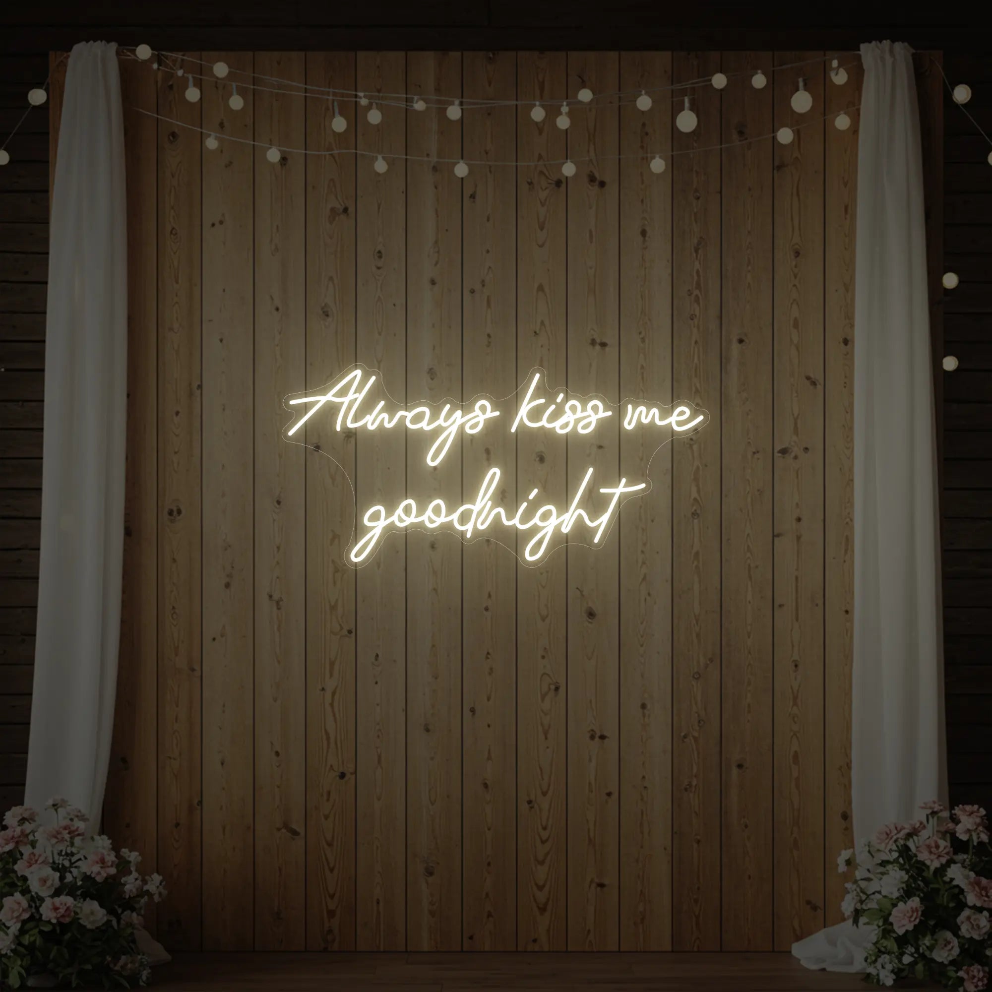 Photo of the 'Always Kiss Me Goodnight' neon sign glowing in warm white against a styled interior wall.