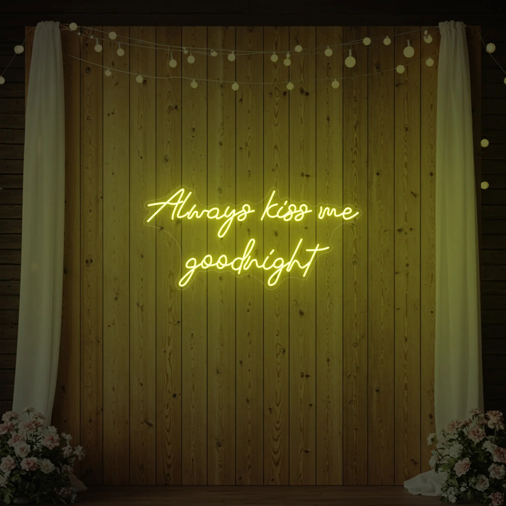 Photo of the 'Always Kiss Me Goodnight' neon sign glowing in lemon yellow against a styled interior wall.