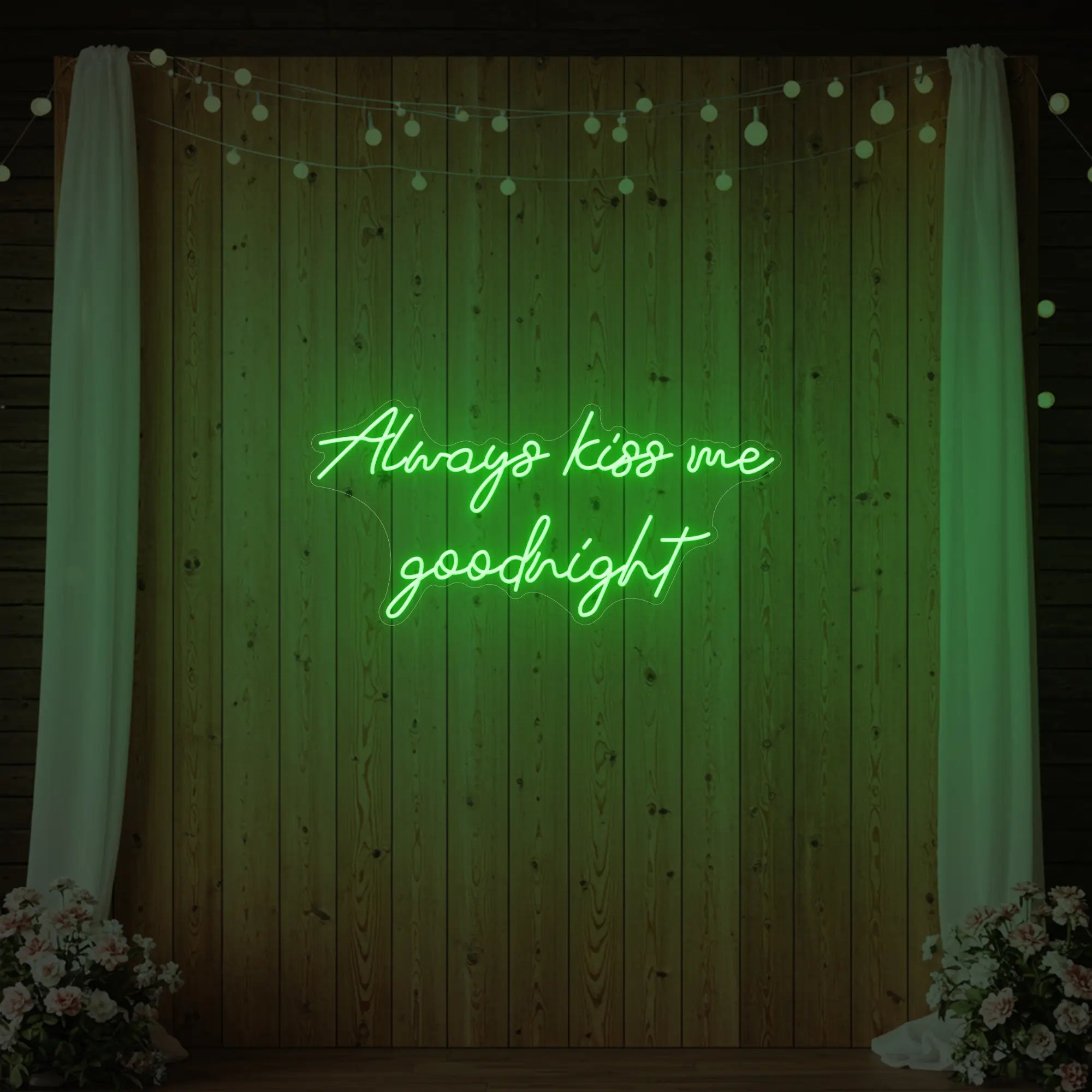 Photo of the 'Always Kiss Me Goodnight' neon sign glowing in green against a styled interior wall.