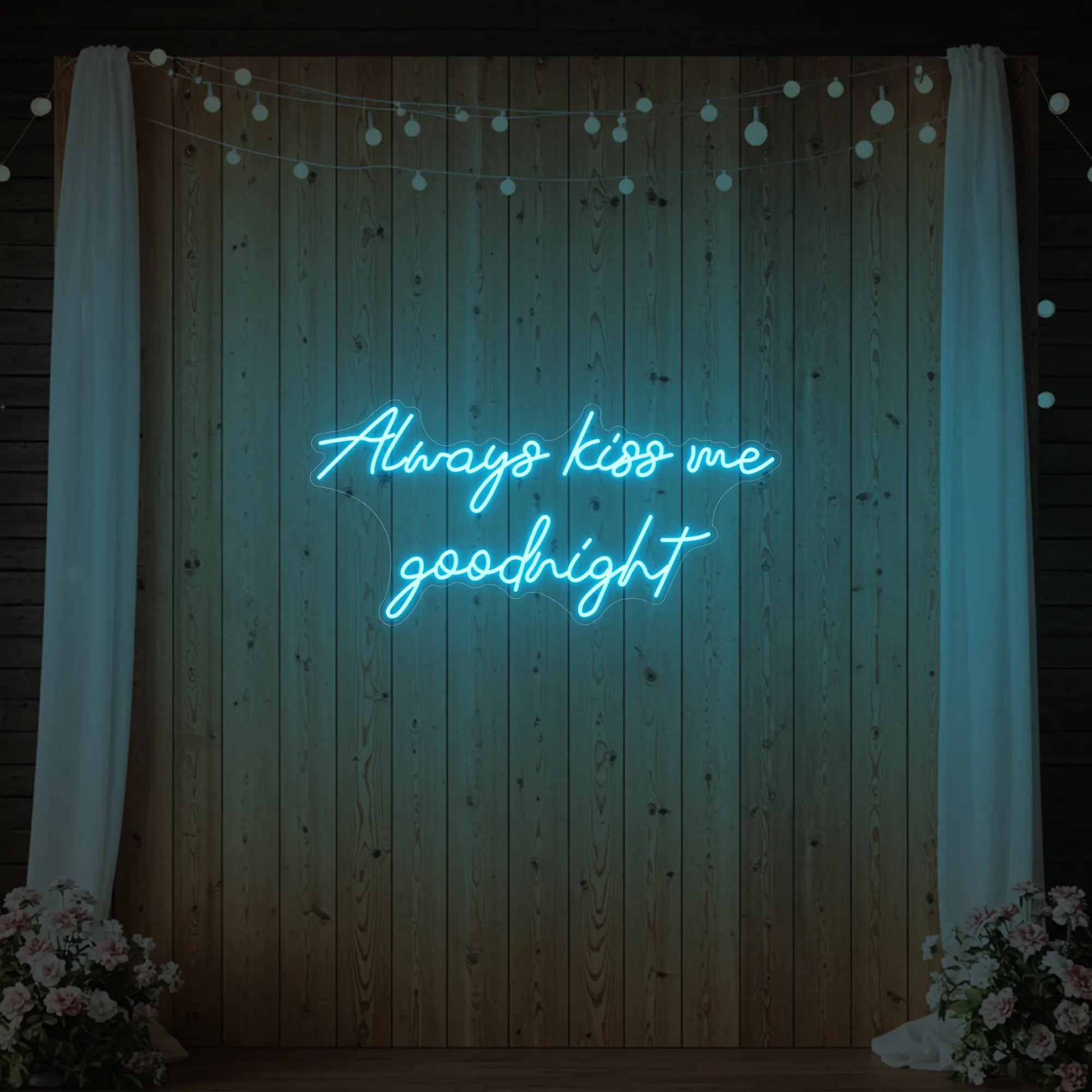 Photo of the 'Always Kiss Me Goodnight' neon sign glowing in ice blue against a styled interior wall.