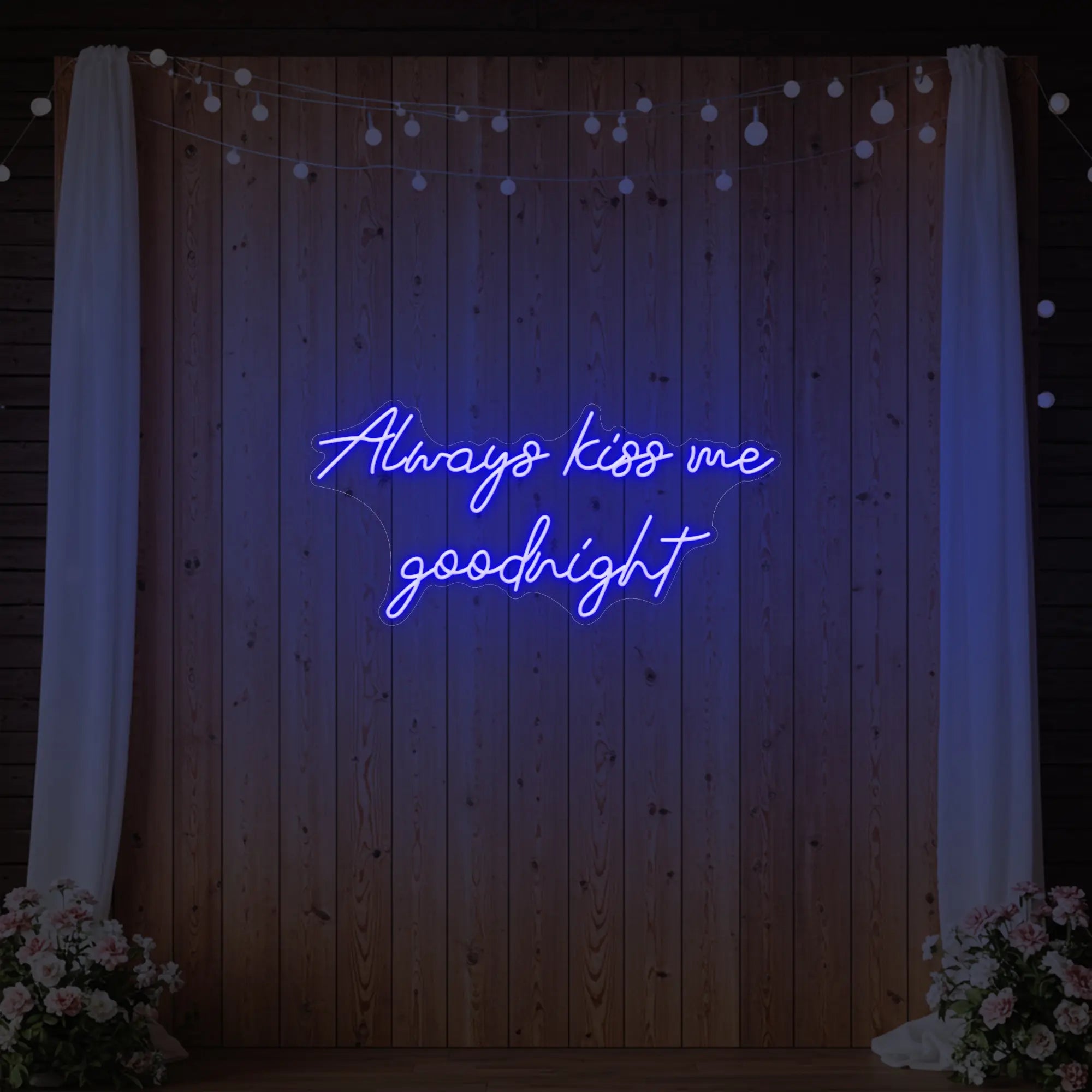 Photo of the 'Always Kiss Me Goodnight' neon sign glowing in deep blue against a styled interior wall.