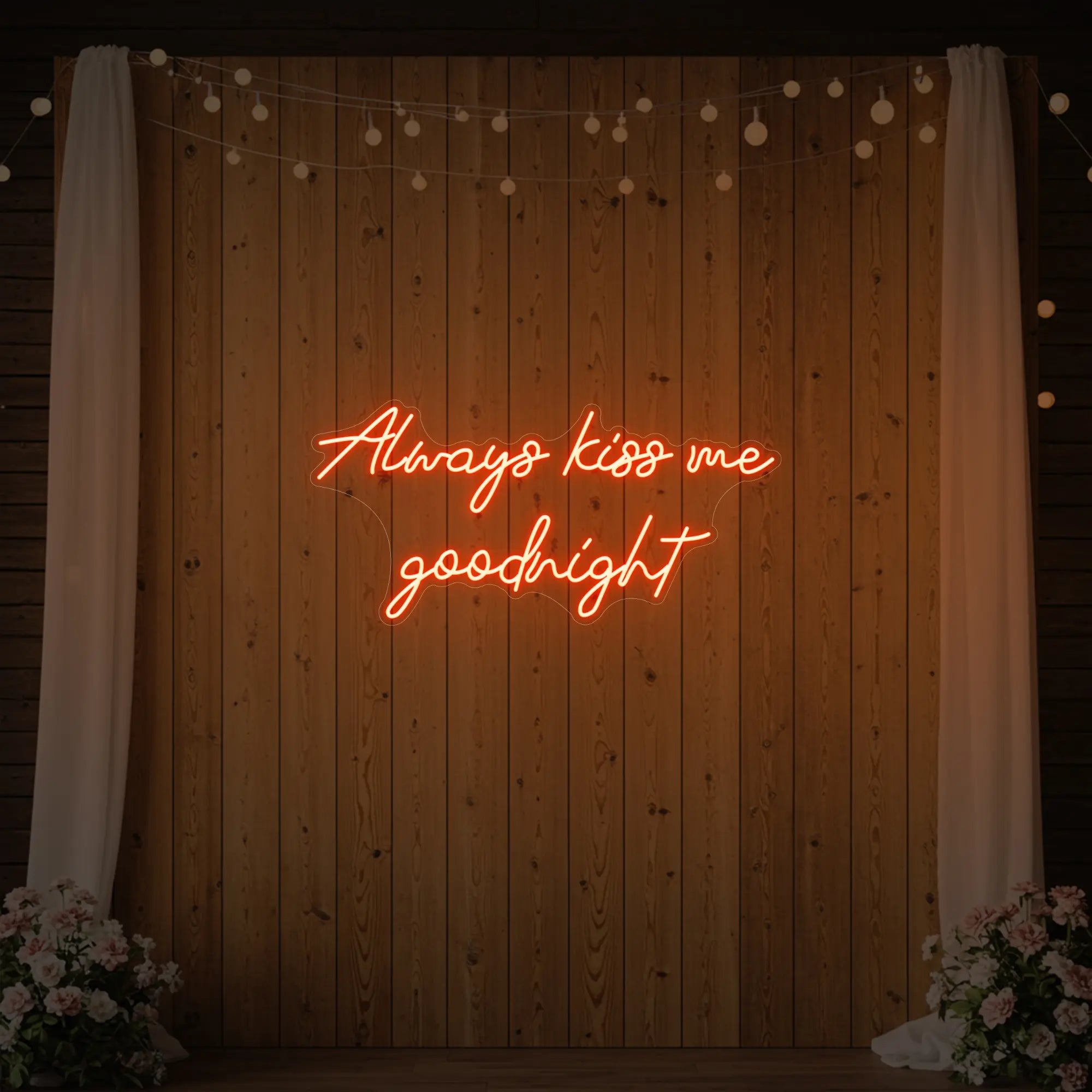 Photo of the 'Always Kiss Me Goodnight' neon sign glowing in golden yellow against a styled interior wall.