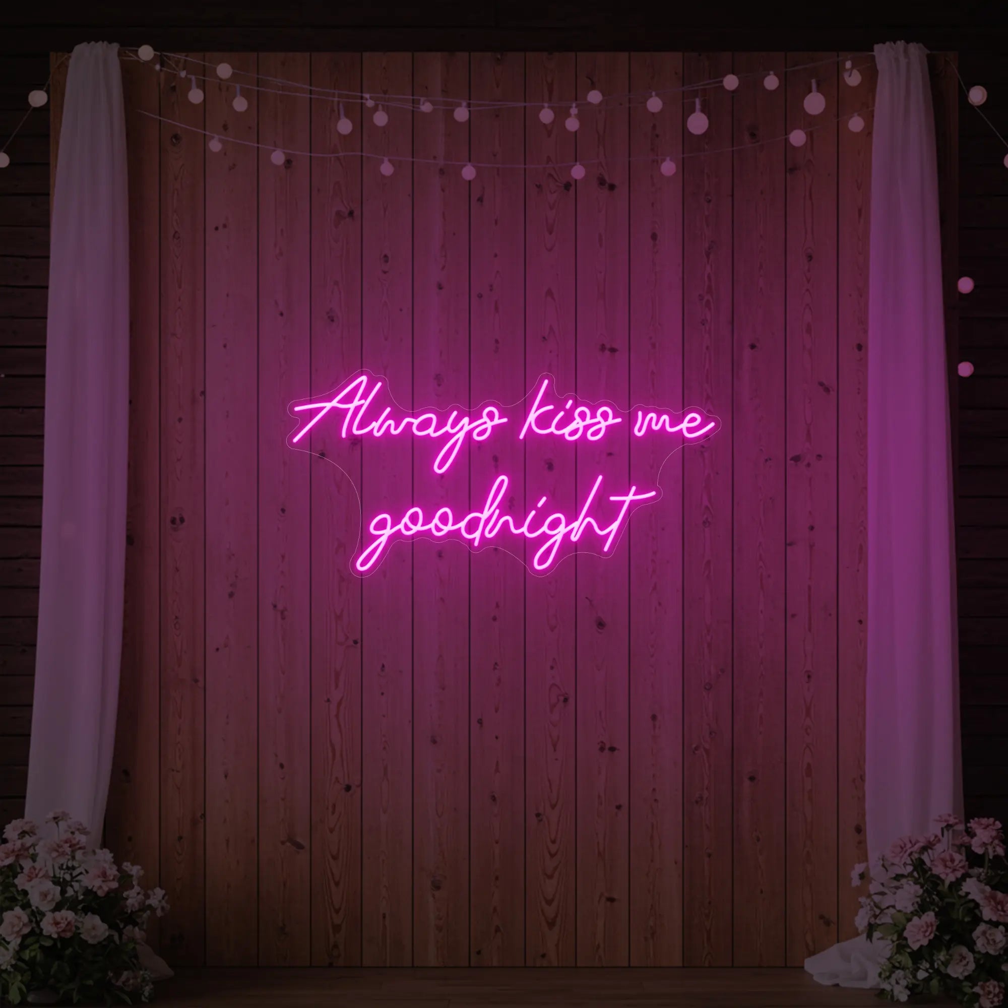 Photo of the 'Always Kiss Me Goodnight' neon sign glowing in light pink against a styled interior wall.