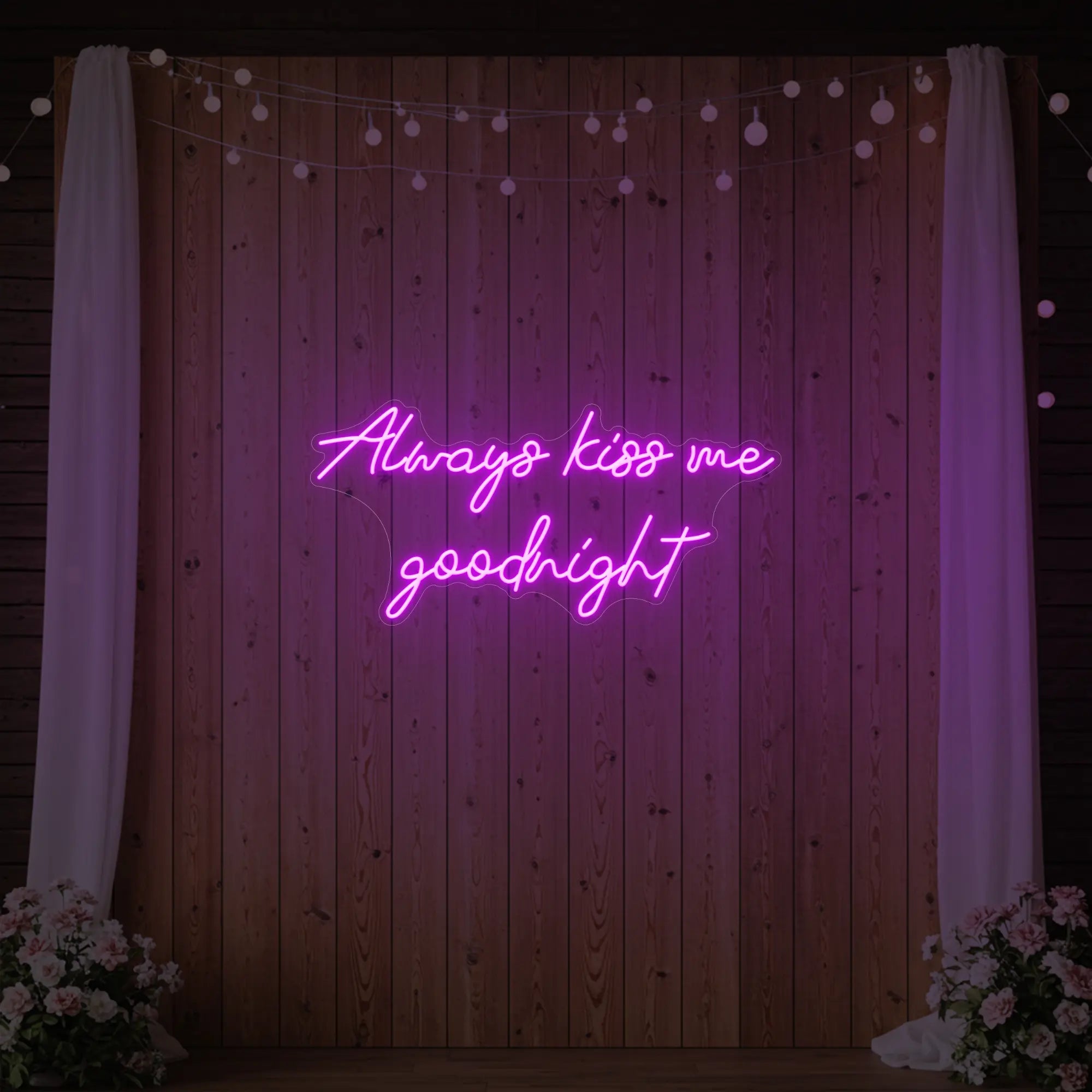 Photo of the 'Always Kiss Me Goodnight' neon sign glowing in deep pink against a styled interior wall.