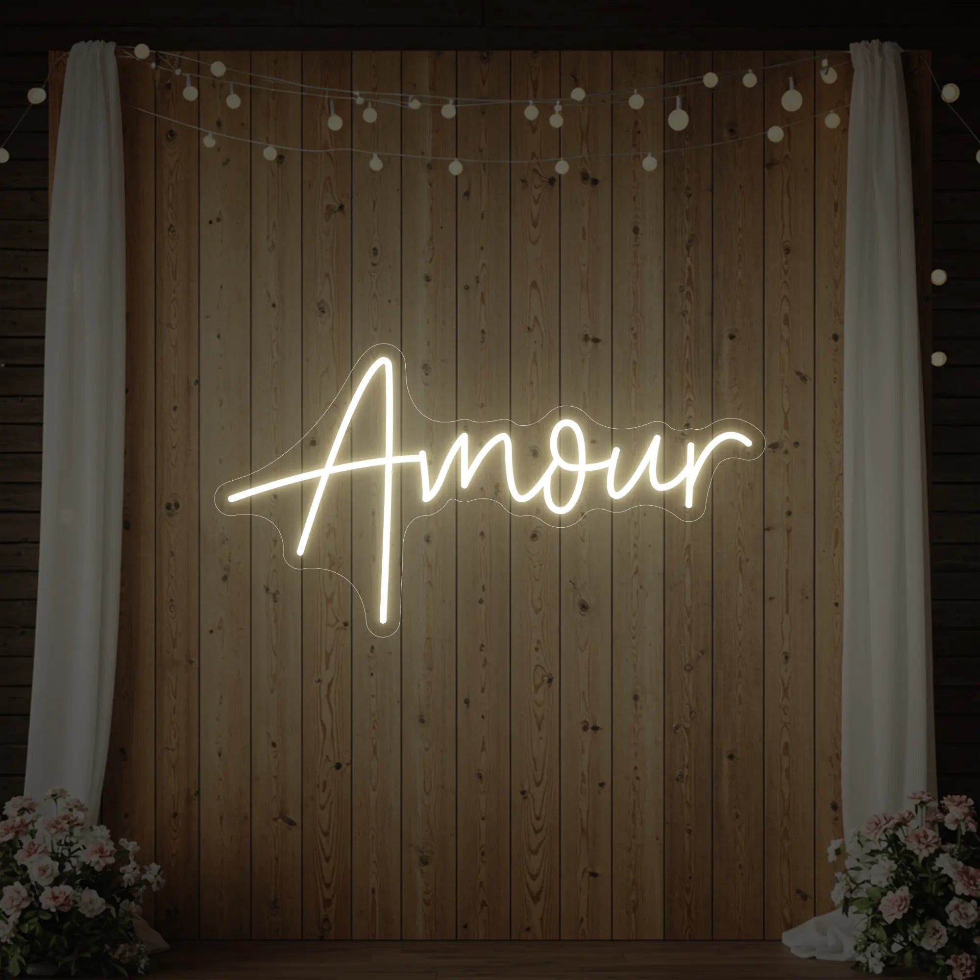 Photo of the 'Amour' neon sign glowing in warm white against a styled interior wall.