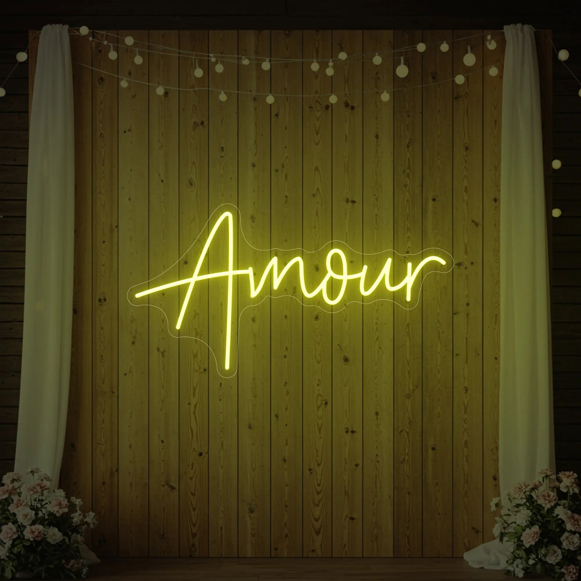 Photo of the 'Amour' neon sign glowing in lemon yellow against a styled interior wall.