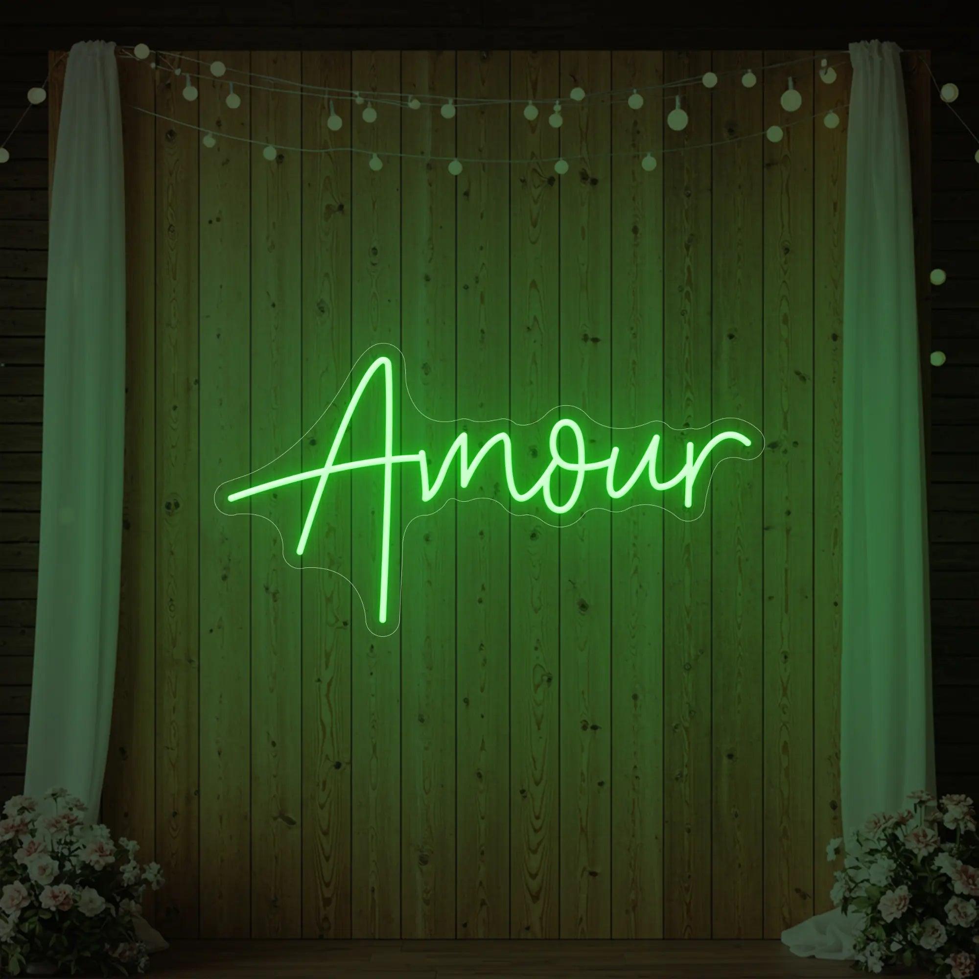 Photo of the 'Amour' neon sign glowing in green against a styled interior wall.
