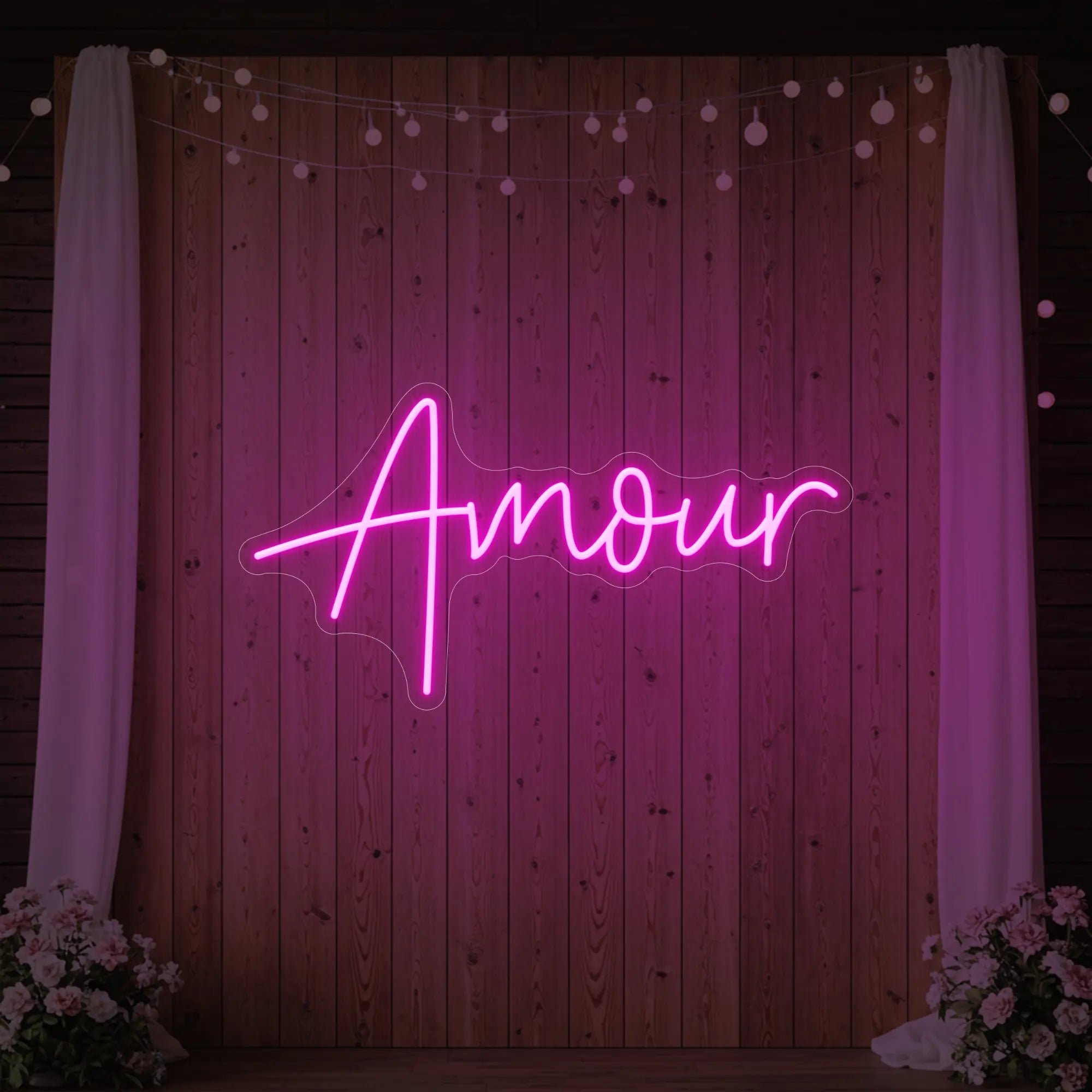 Photo of the 'Amour' neon sign glowing in light pink against a styled interior wall.