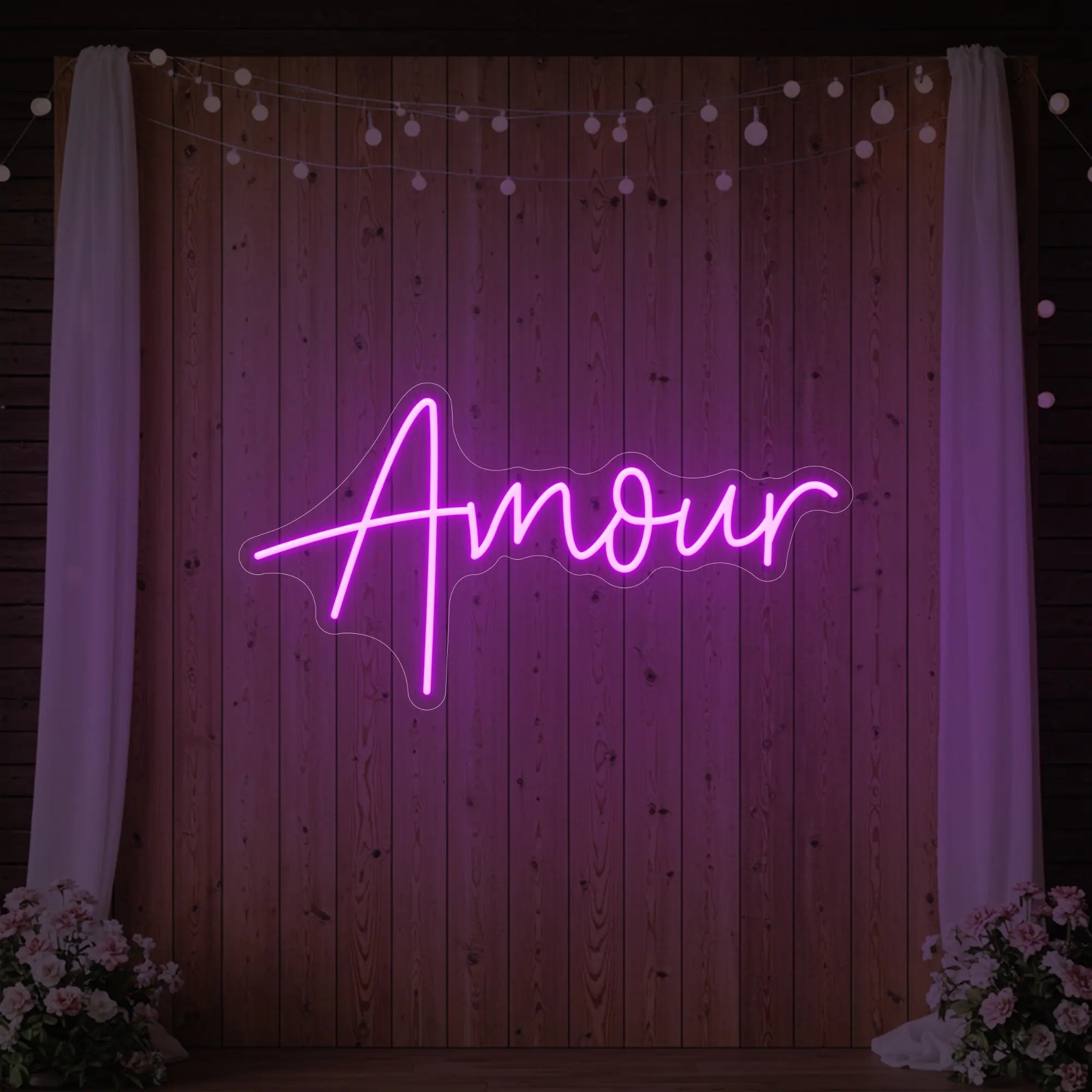 Photo of the 'Amour' neon sign glowing in deep pink against a styled interior wall.