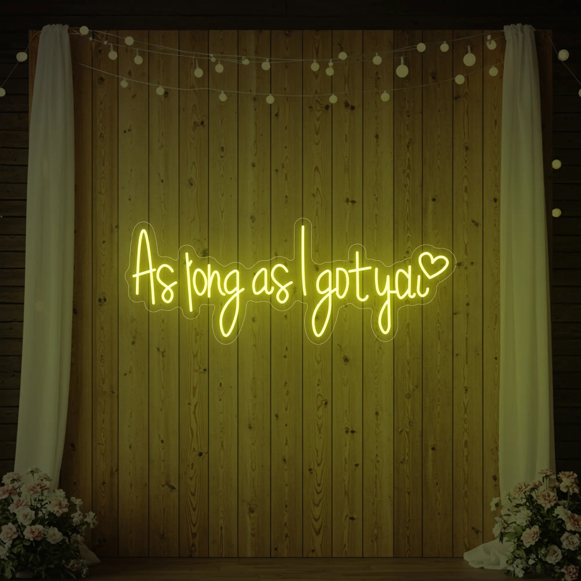 Photo of the 'As Long As I Got You' neon sign glowing in lemon yellow against a styled interior wall.