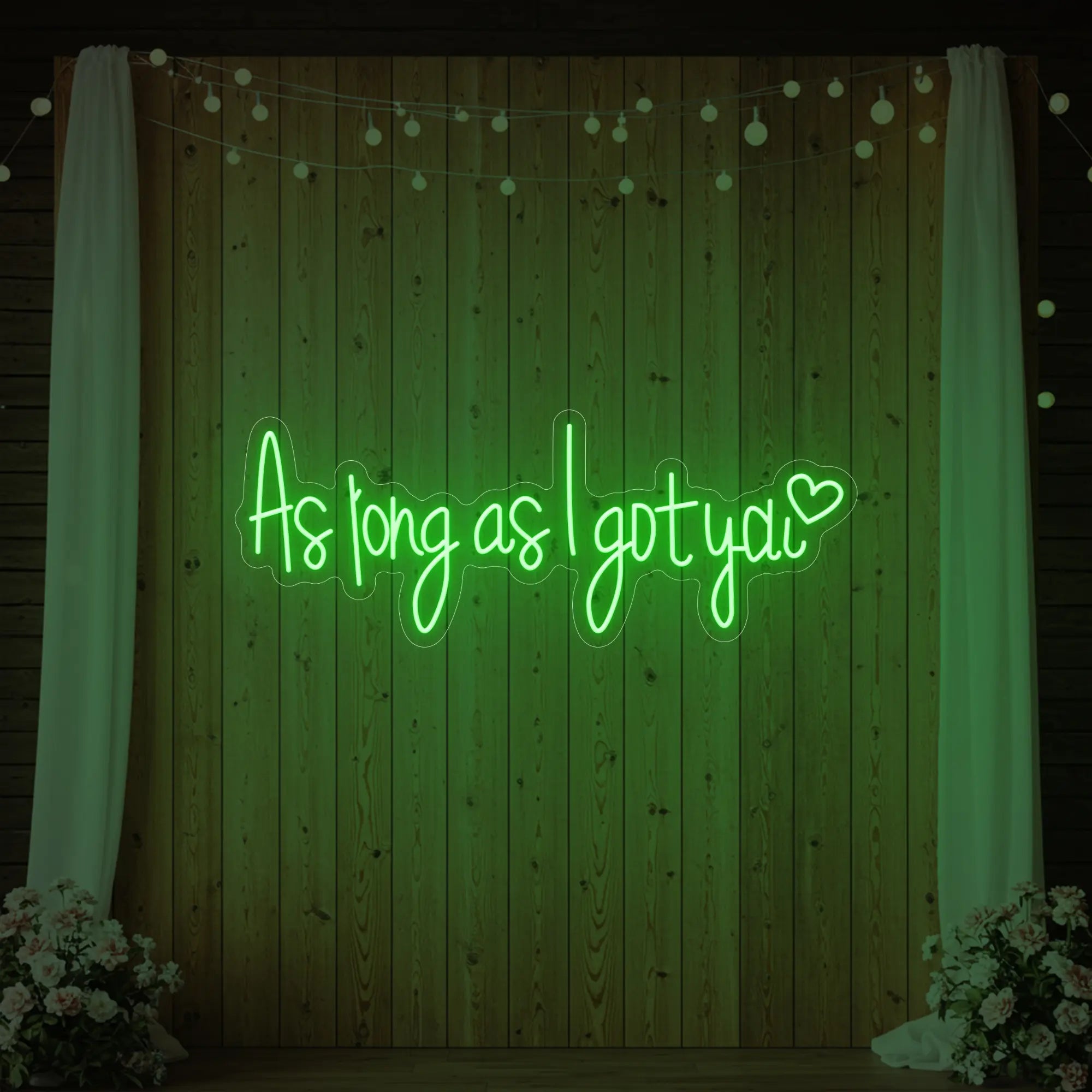 Photo of the 'As Long As I Got You' neon sign glowing in green against a styled interior wall.