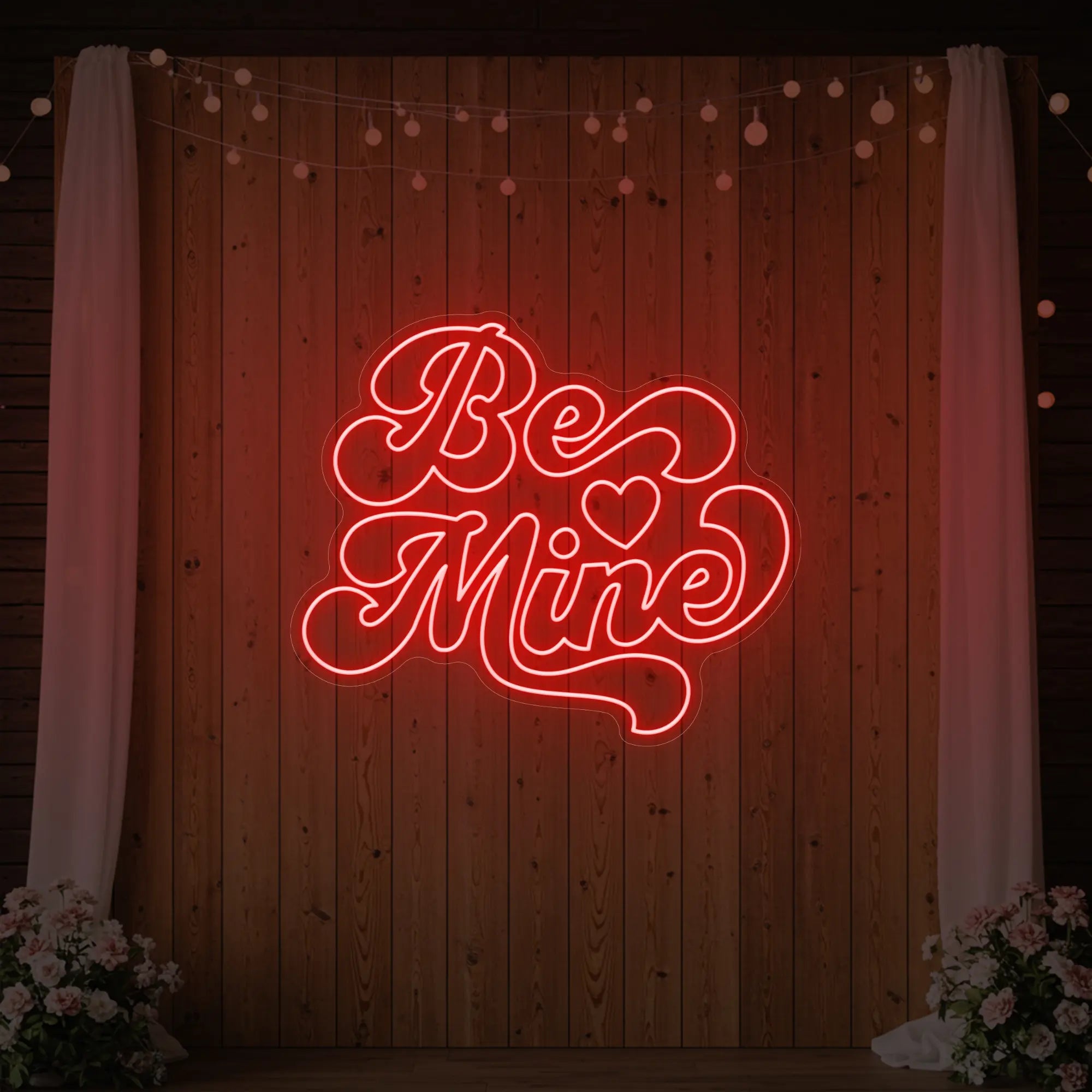 Photo of the 'Be Mine' neon sign glowing in red against a styled interior wall.