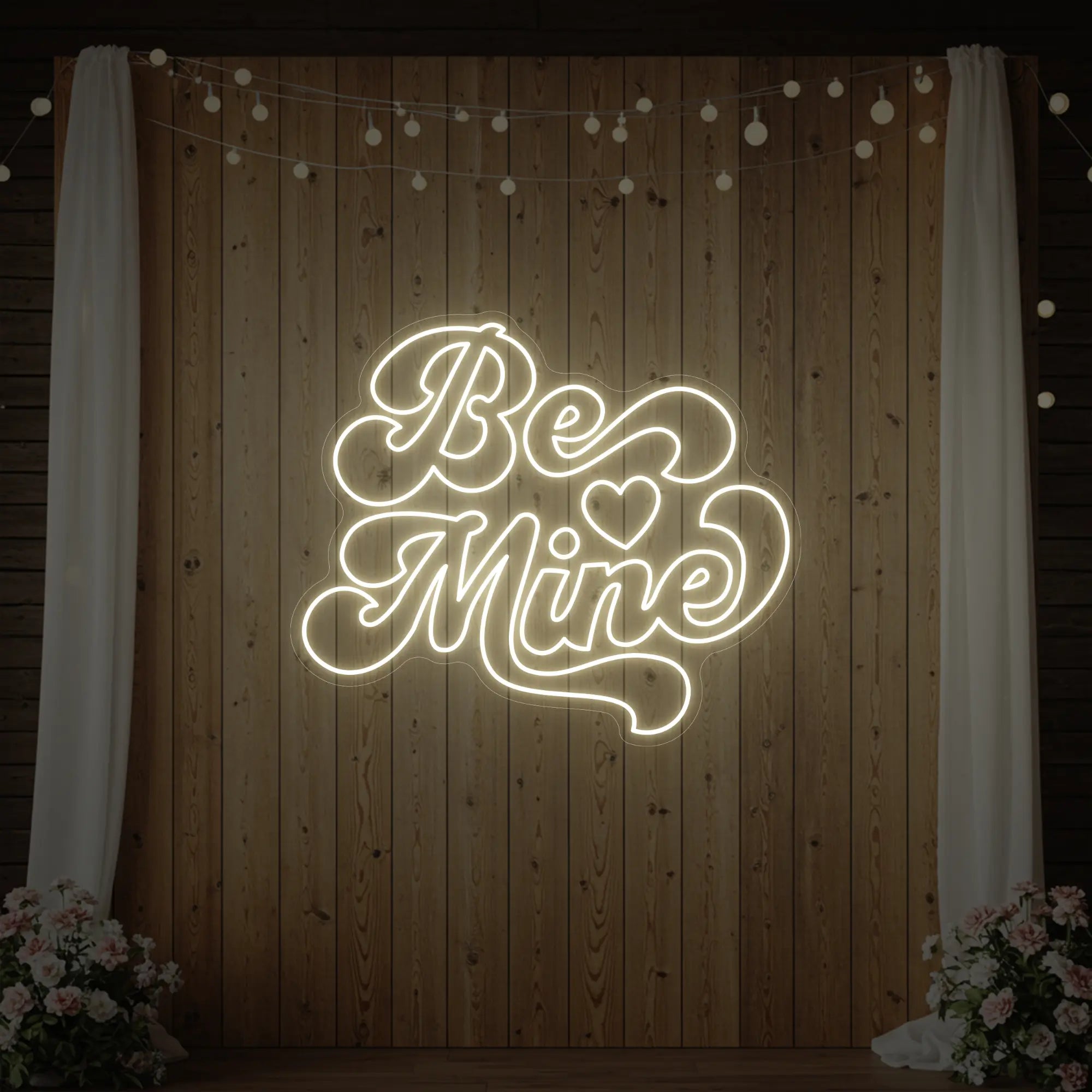 Photo of the 'Be Mine' neon sign glowing in warm white against a styled interior wall.