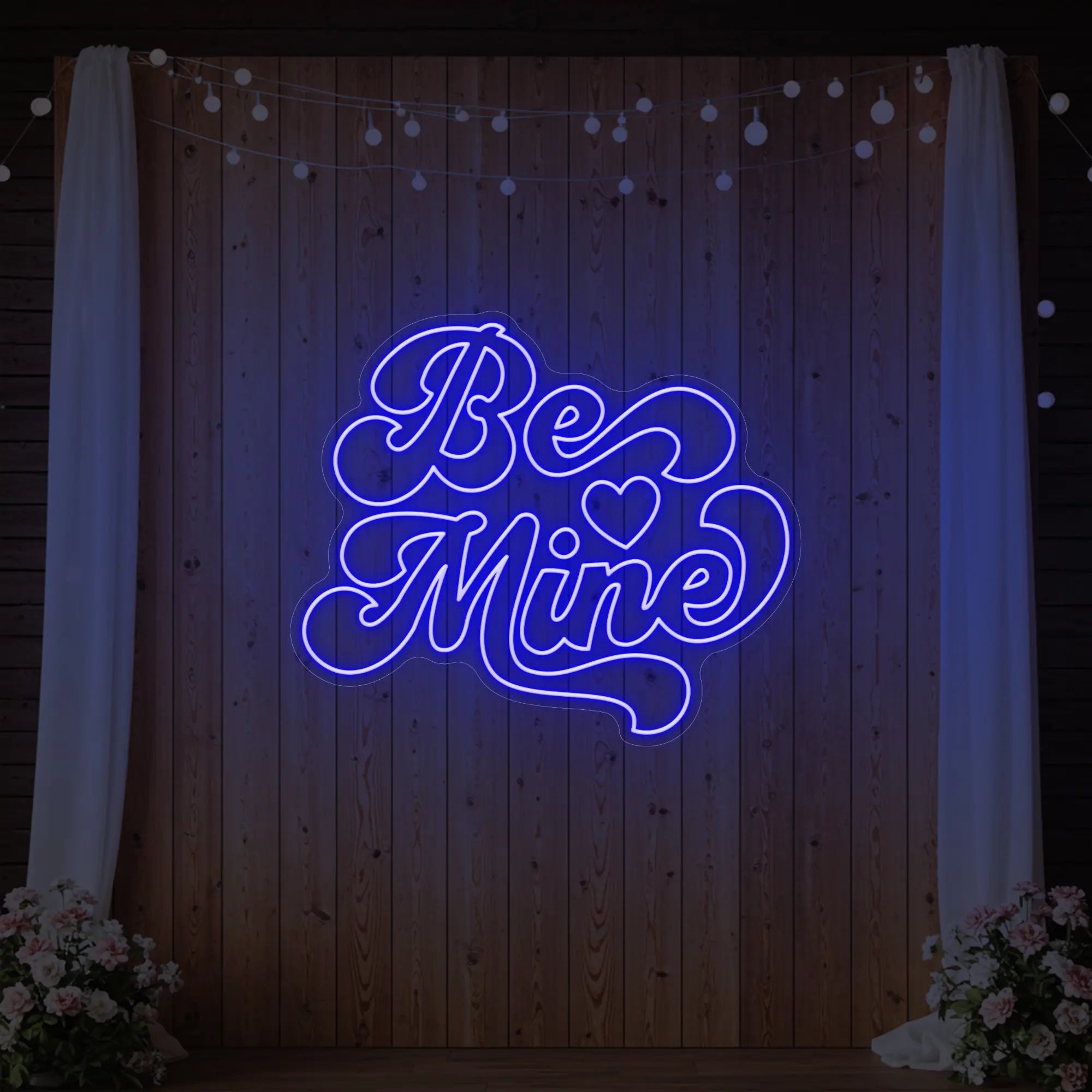 Photo of the 'Be Mine' neon sign glowing in deep blue against a styled interior wall.