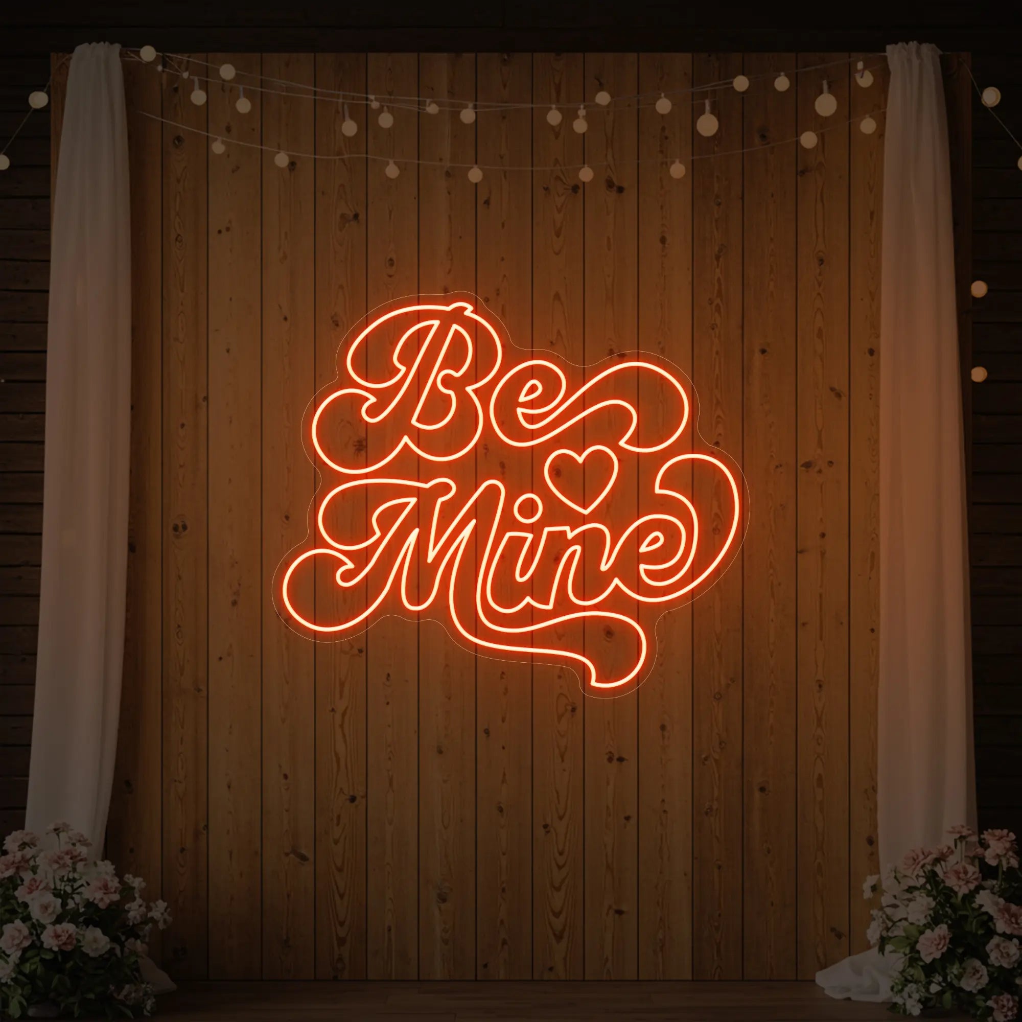 Photo of the 'Be Mine' neon sign glowing in golden yellow against a styled interior wall.