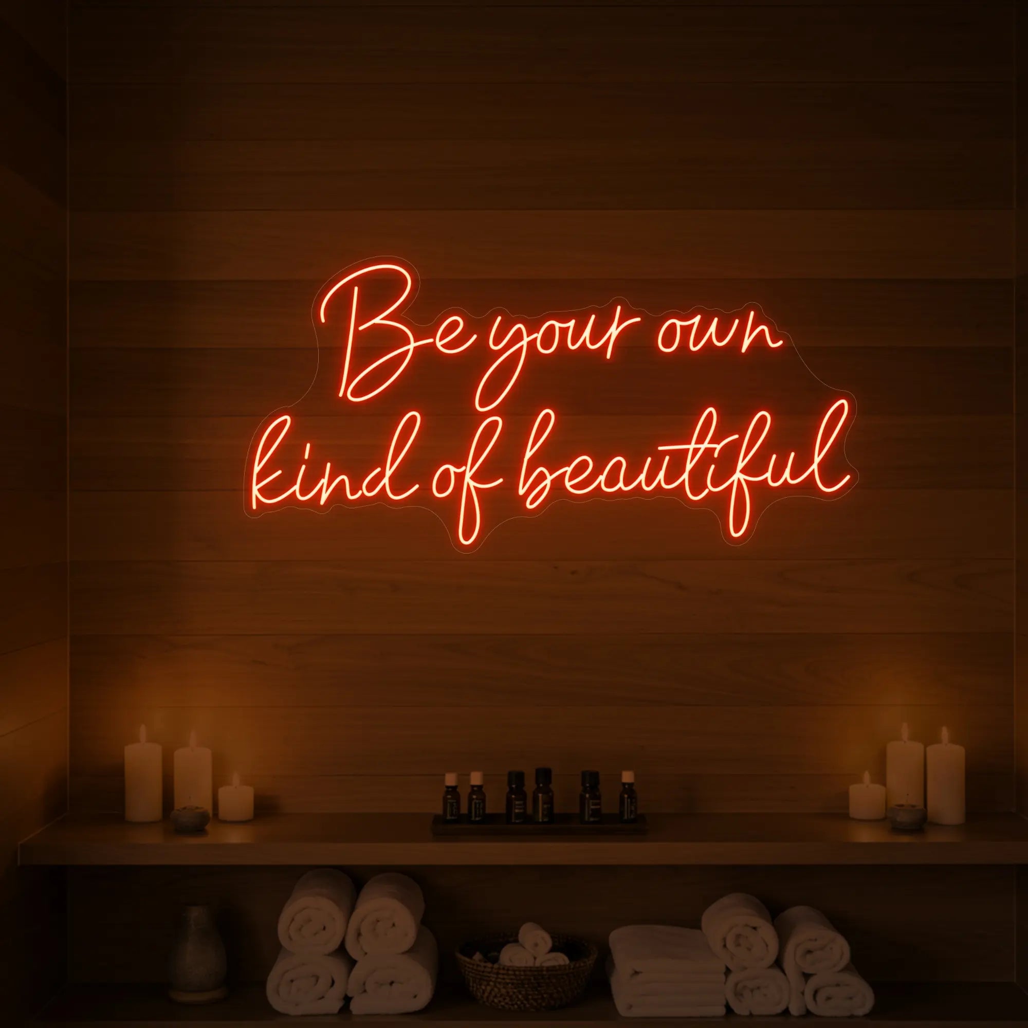 Photo of the 'Be Your Own Kind of Beautiful' neon sign glowing in golden yellow against a styled interior wall.