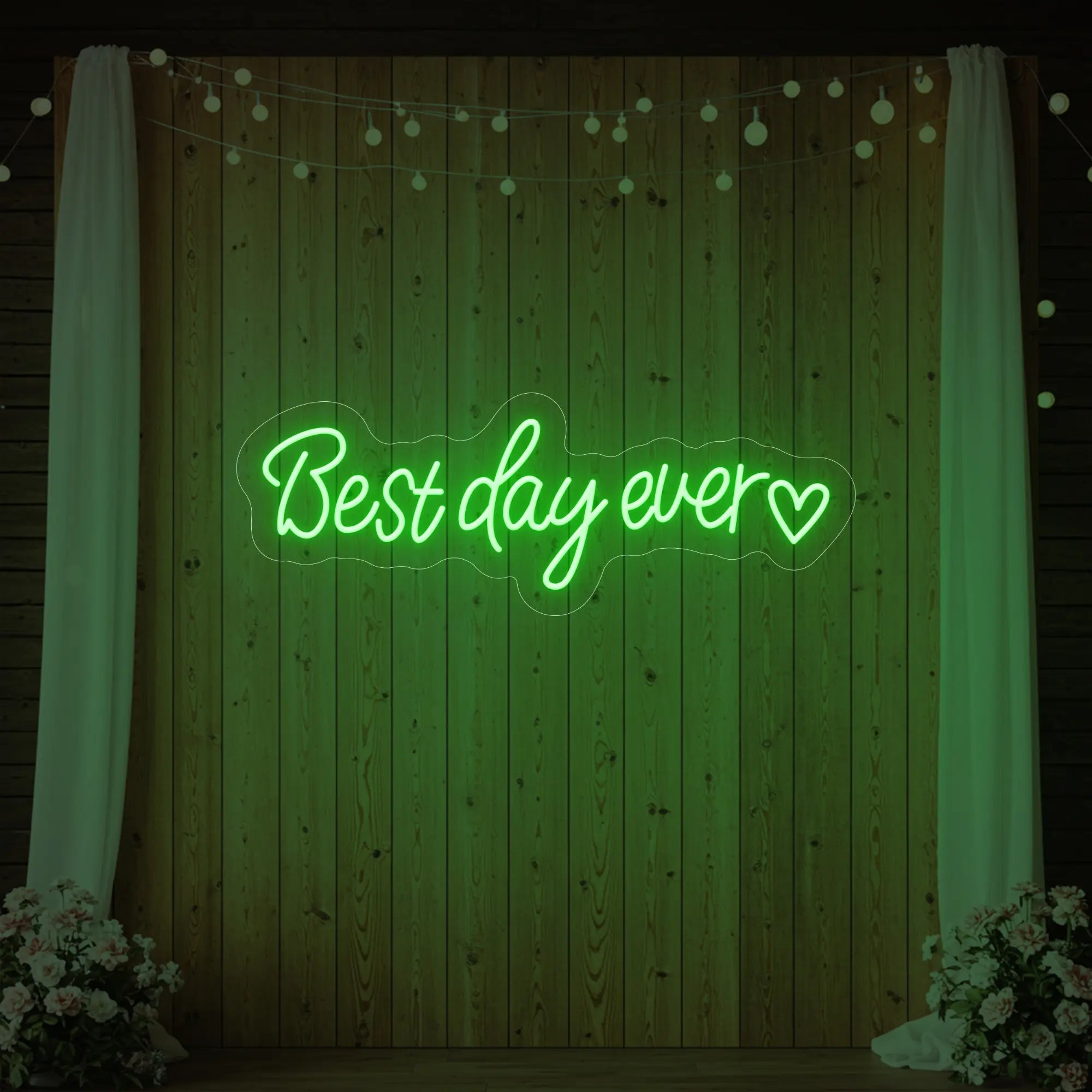 Photo of the 'Best Day Ever Heart' neon sign glowing in green against a styled interior wall.