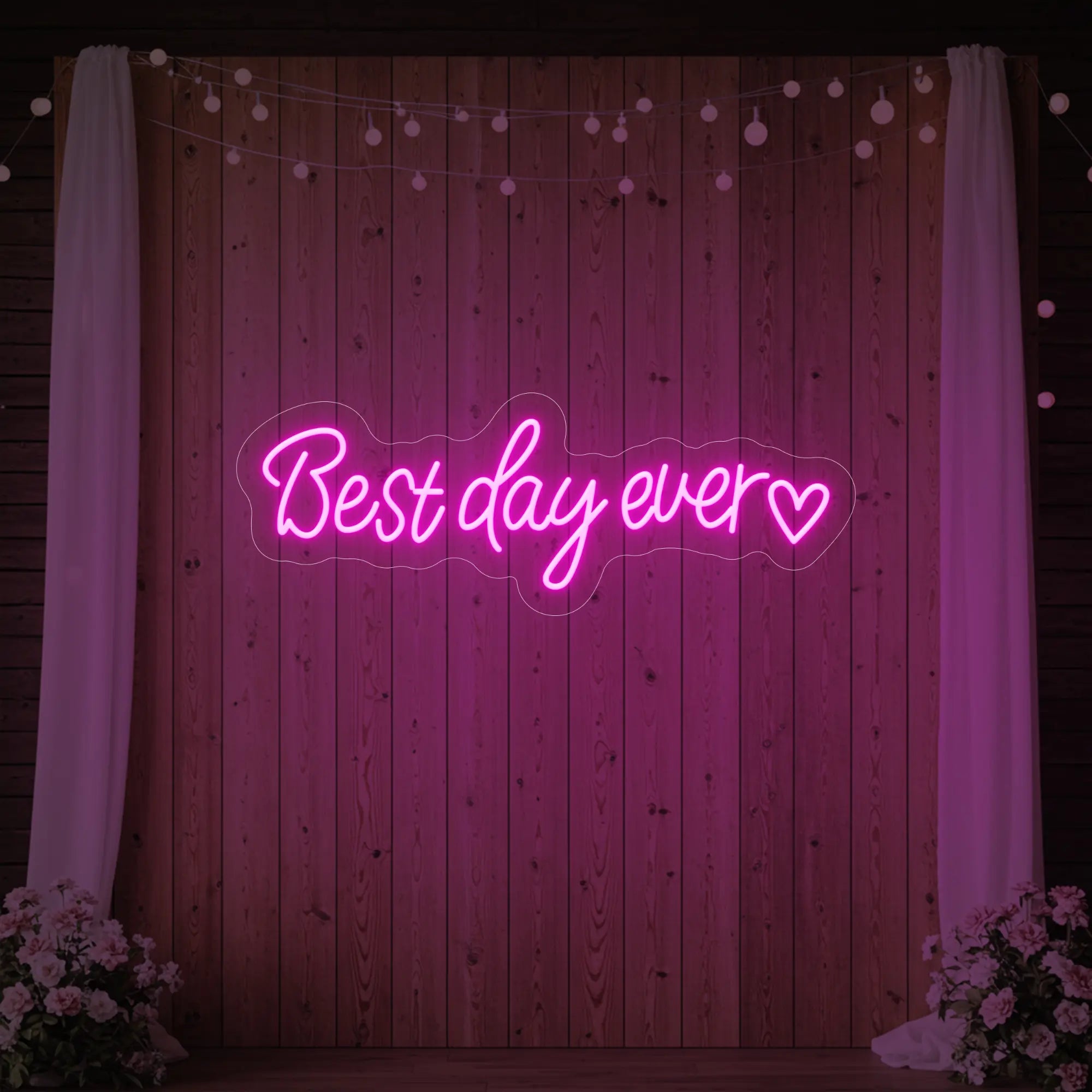 Photo of the 'Best Day Ever Heart' neon sign glowing in light pink against a styled interior wall.