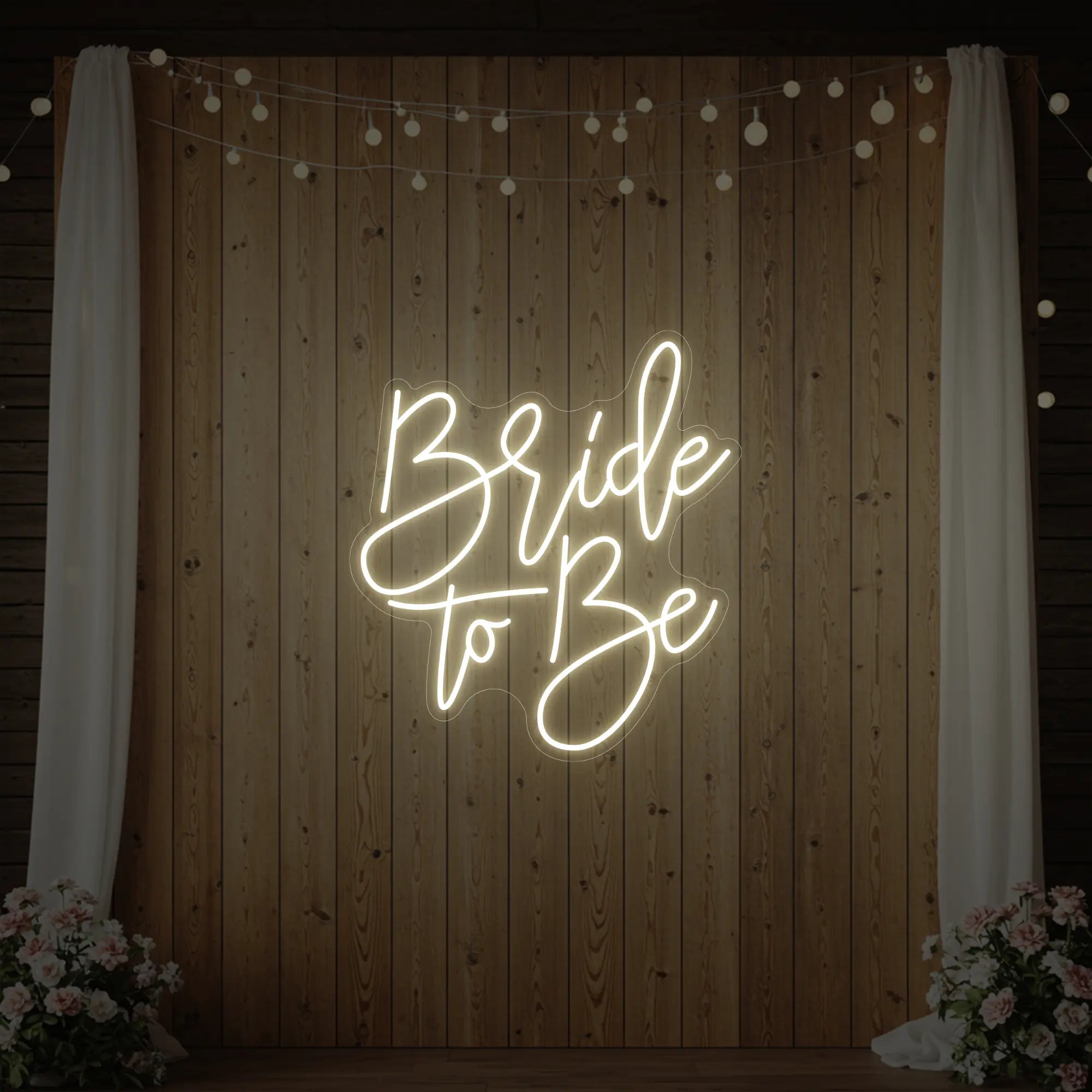 Photo of the 'Bride To Be' neon sign glowing in warm white against a styled interior wall.