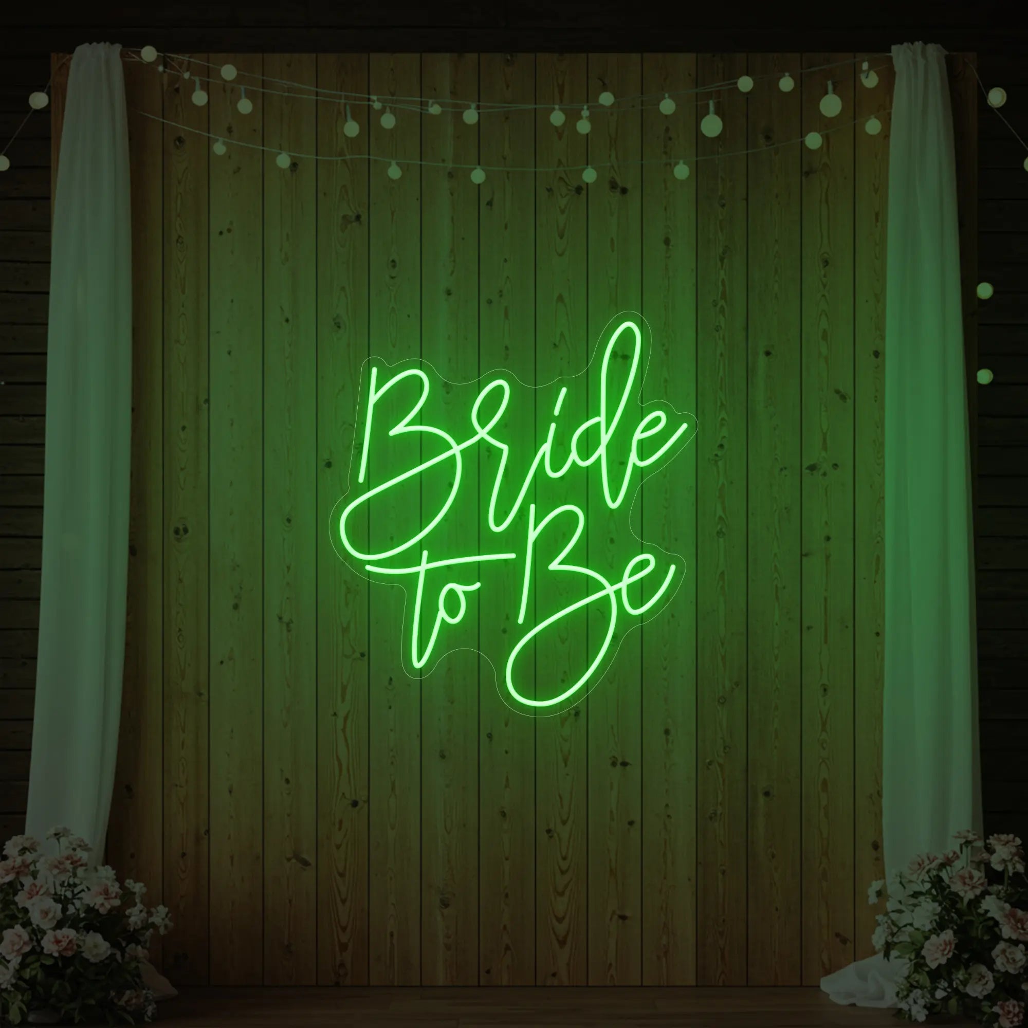 Photo of the 'Bride To Be' neon sign glowing in green against a styled interior wall.