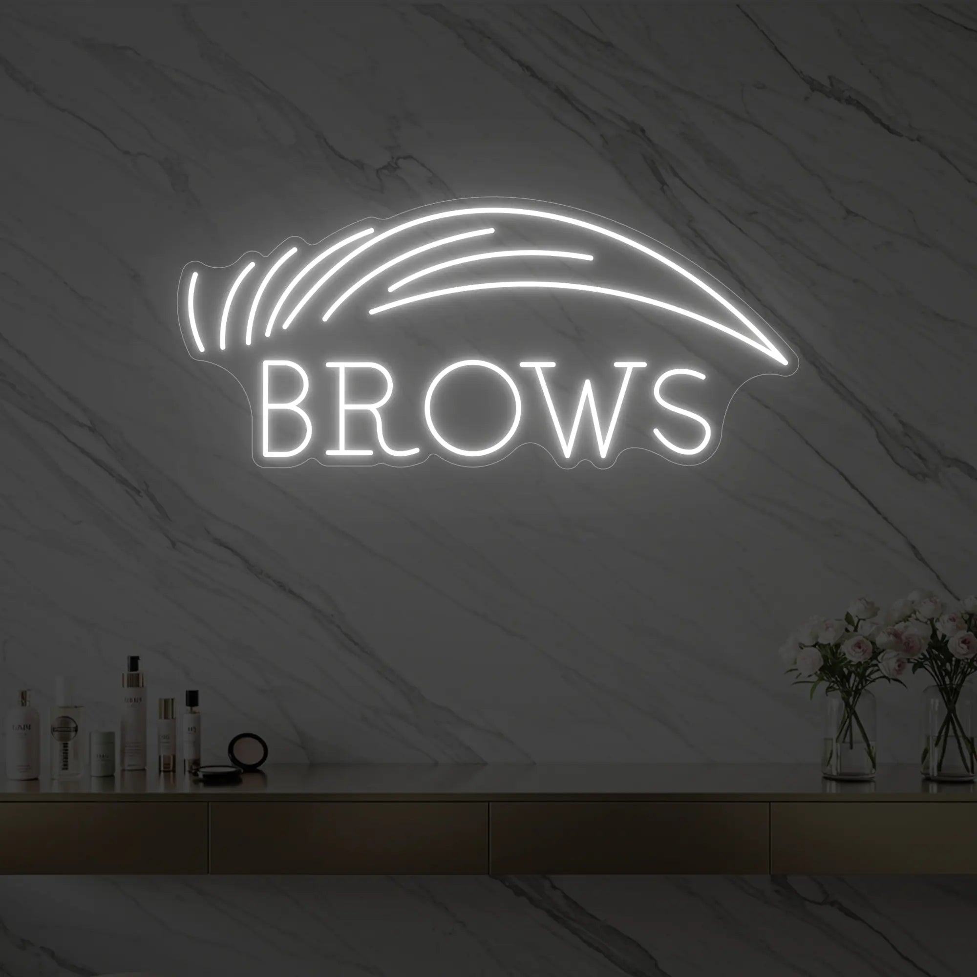Photo of the 'BROWS' neon sign with an eyebrow graphic glowing in cool white against a styled interior wall.