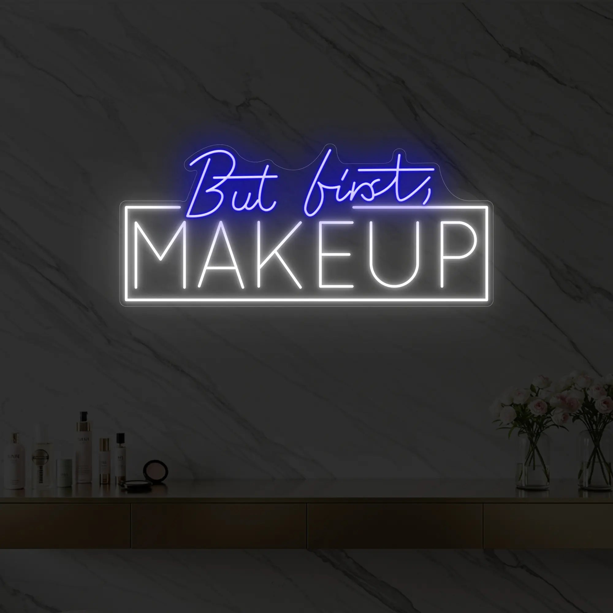 Photo of the 'But first, MAKEUP' neon sign glowing in deep blue against a styled interior wall.