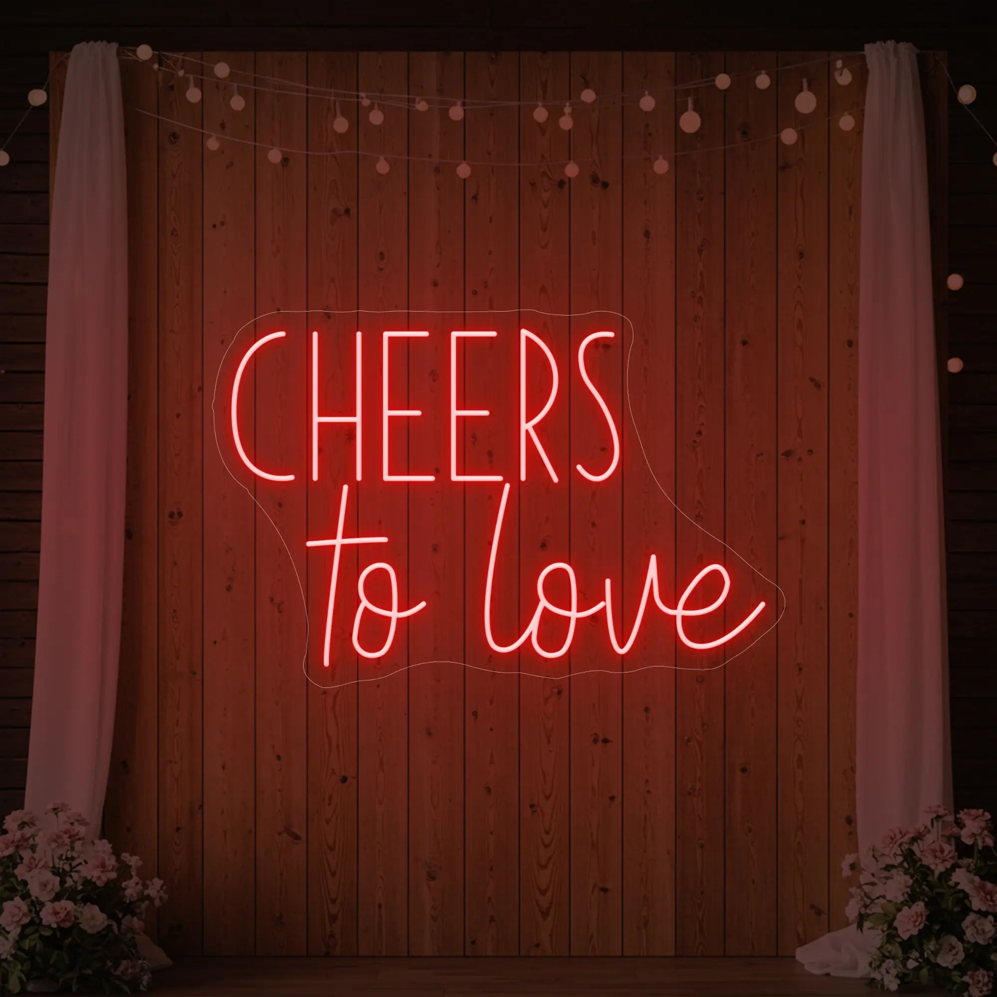 Photo of the 'Cheers To Love' neon sign glowing in red against a styled interior wall.