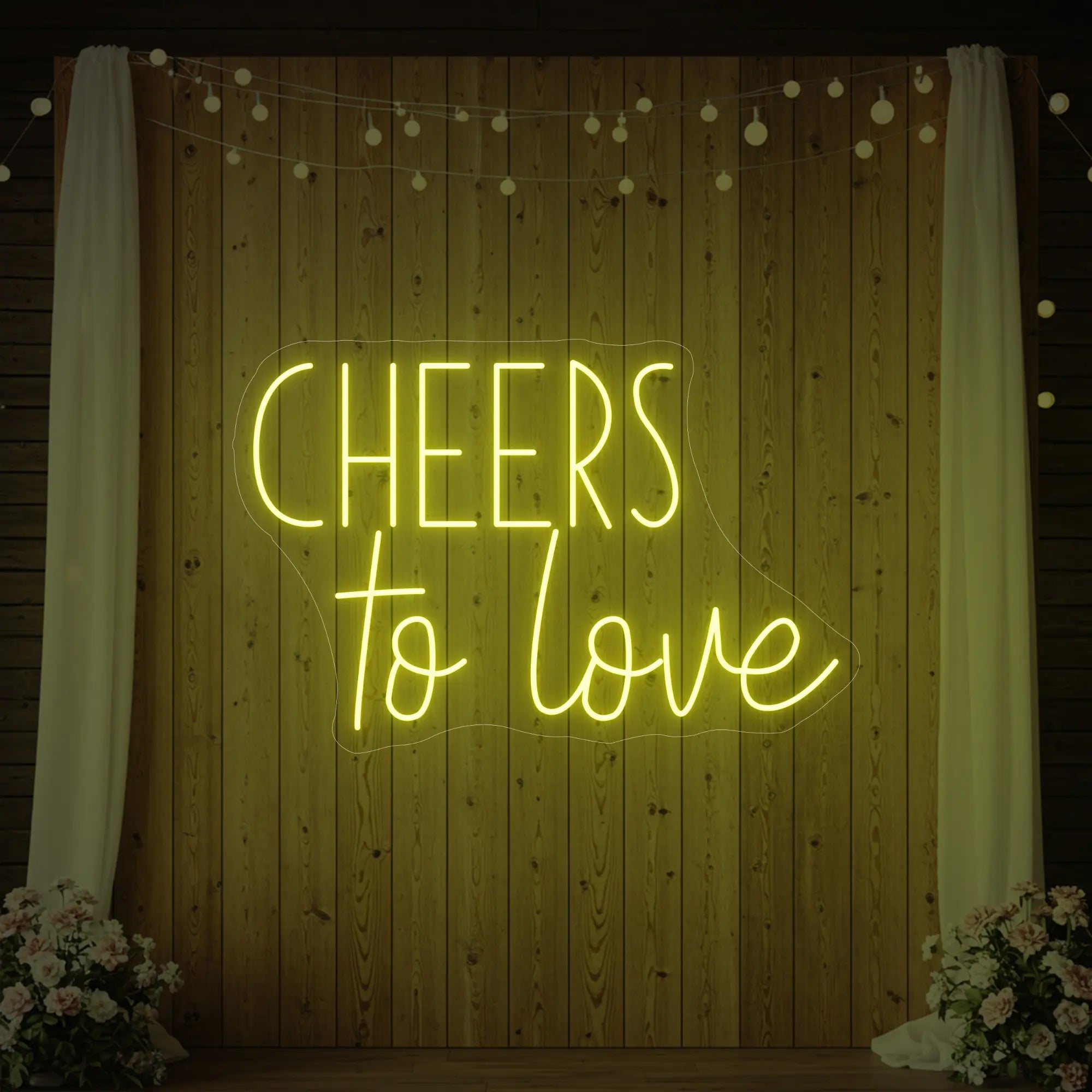 Photo of the 'Cheers To Love' neon sign glowing in lemon yellow against a styled interior wall.