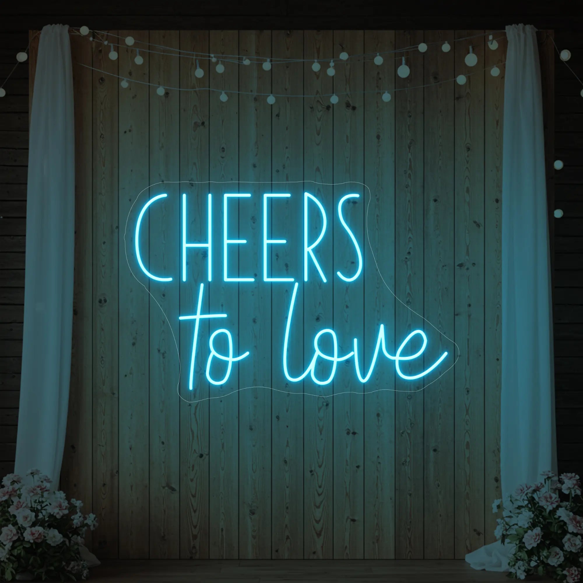 Photo of the 'Cheers To Love' neon sign glowing in ice blue against a styled interior wall.