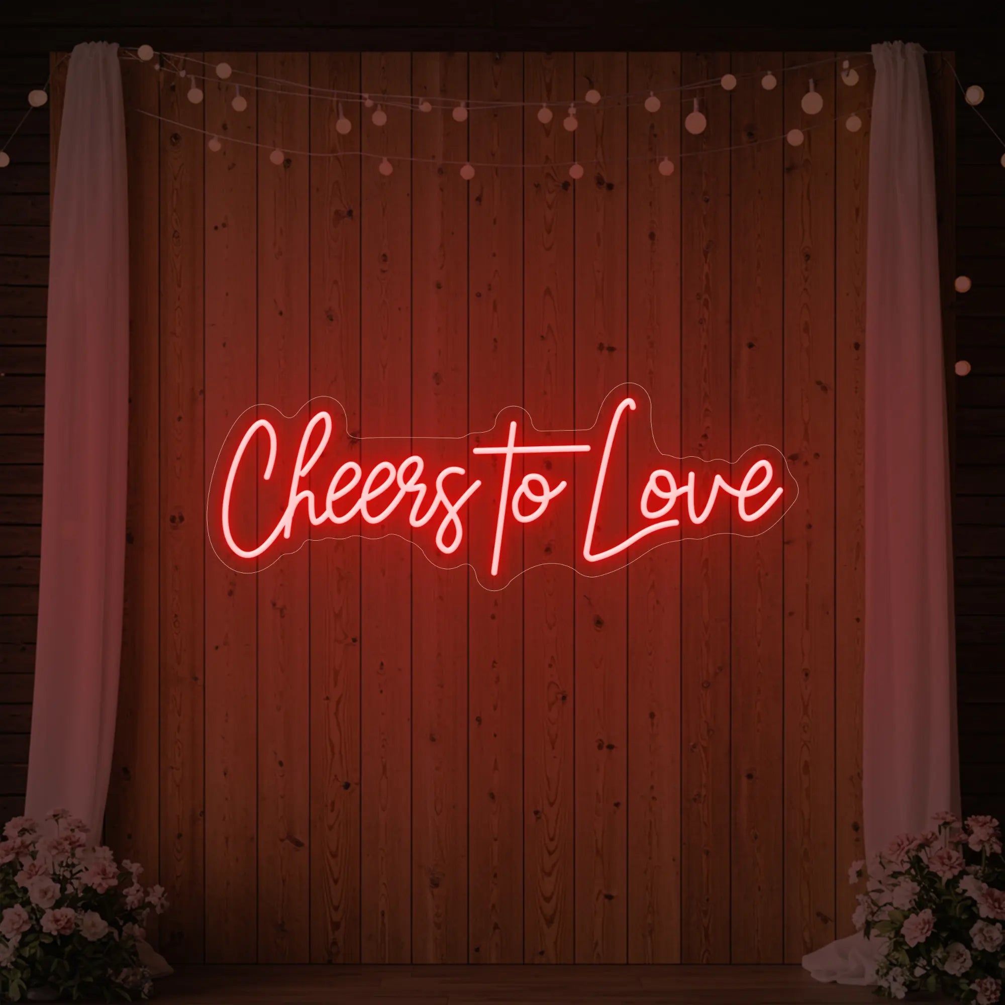 Photo of the 'Cheers To Love' neon sign glowing in red against a styled interior wall.