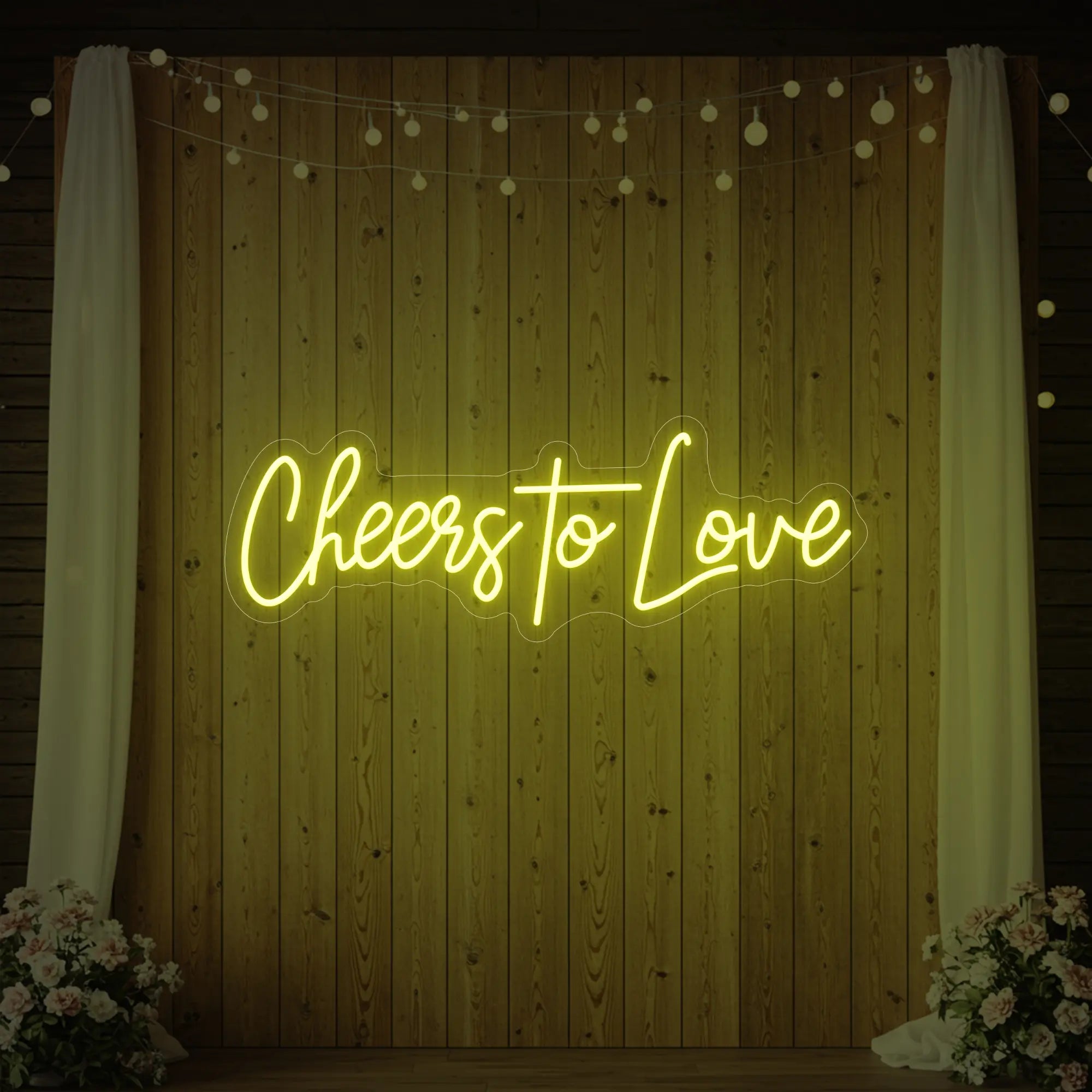 Photo of the 'Cheers To Love' neon sign glowing in lemon yellow against a styled interior wall.