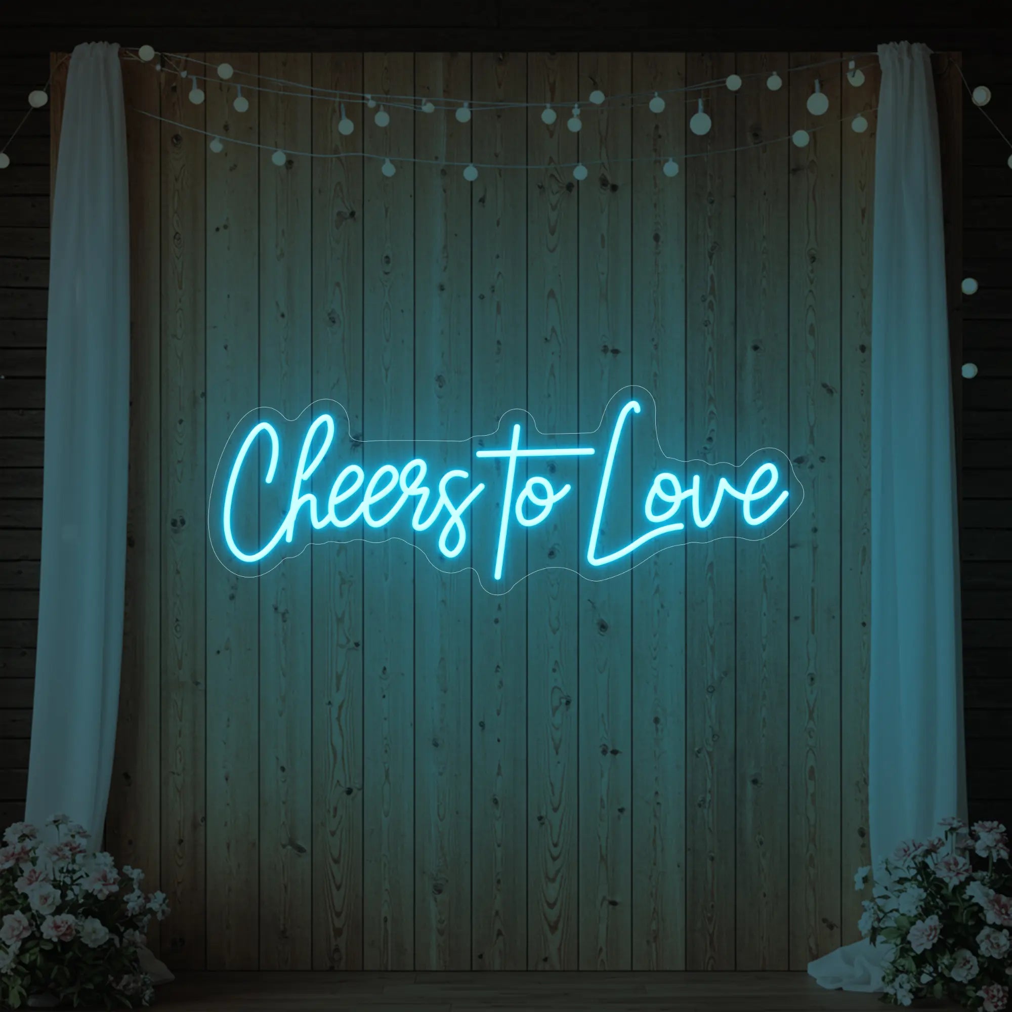 Photo of the 'Cheers To Love' neon sign glowing in ice blue against a styled interior wall.