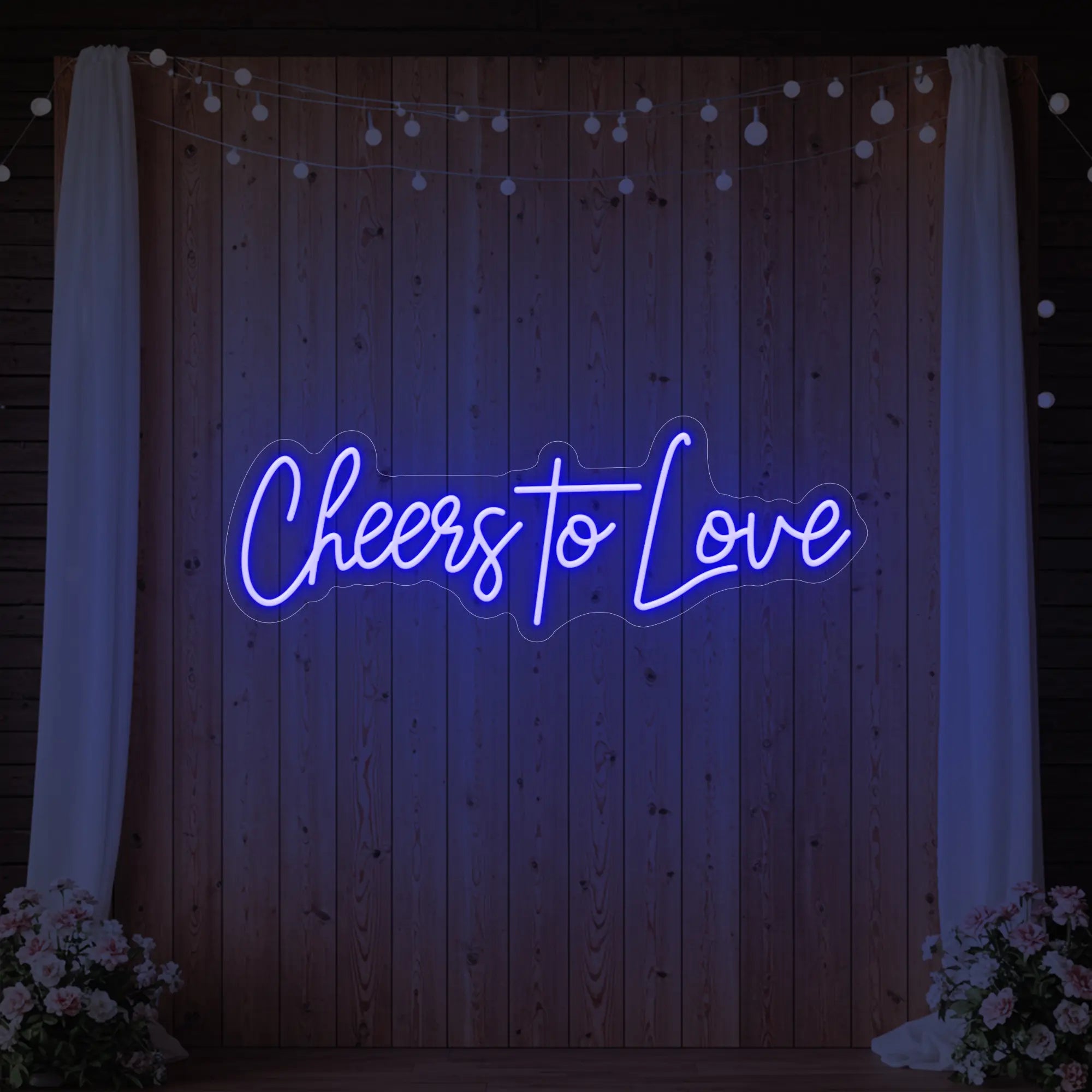 Photo of the 'Cheers To Love' neon sign glowing in deep blue against a styled interior wall.
