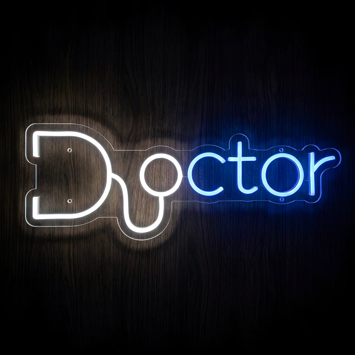 Doctor Stethoscope Typography LED Neon Sign featuring the word Doctor in blue and white glowing letters with a white stethoscope integrated into the design, mounted on clear acrylic against a dark wooden wall.