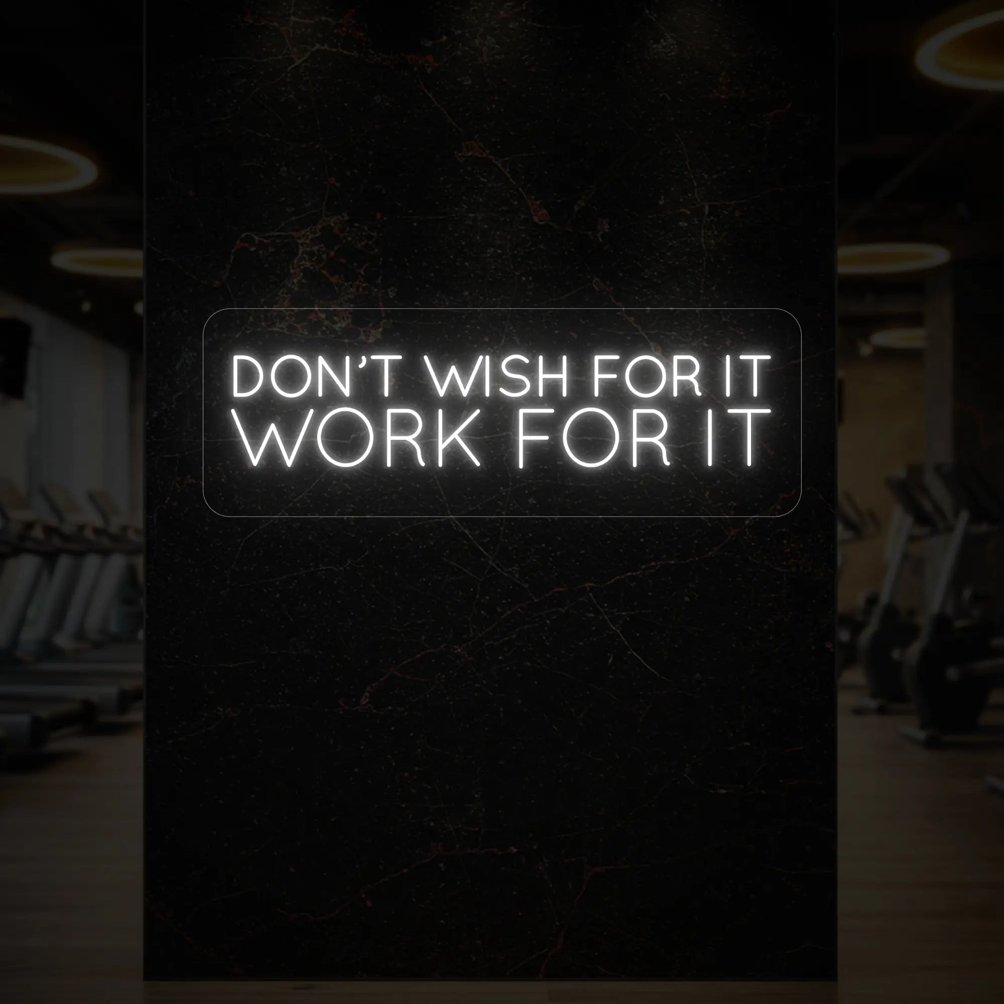 'Don’t Wish For It, Work For It' neon sign glowing in cool white against a styled interior wall.