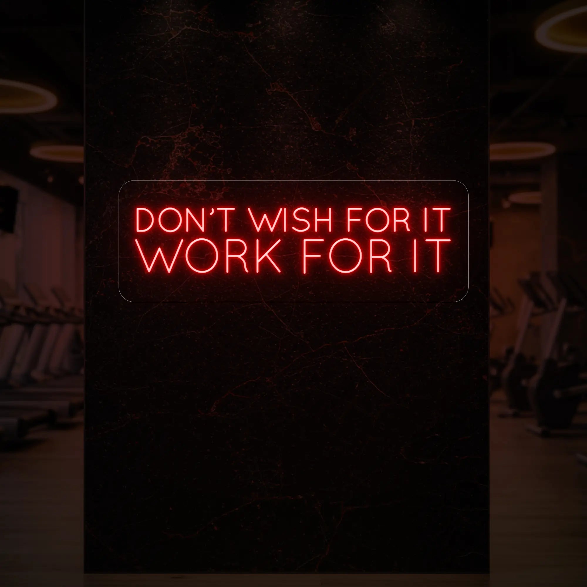 'Don’t Wish For It, Work For It' neon sign glowing in red against a styled interior wall.