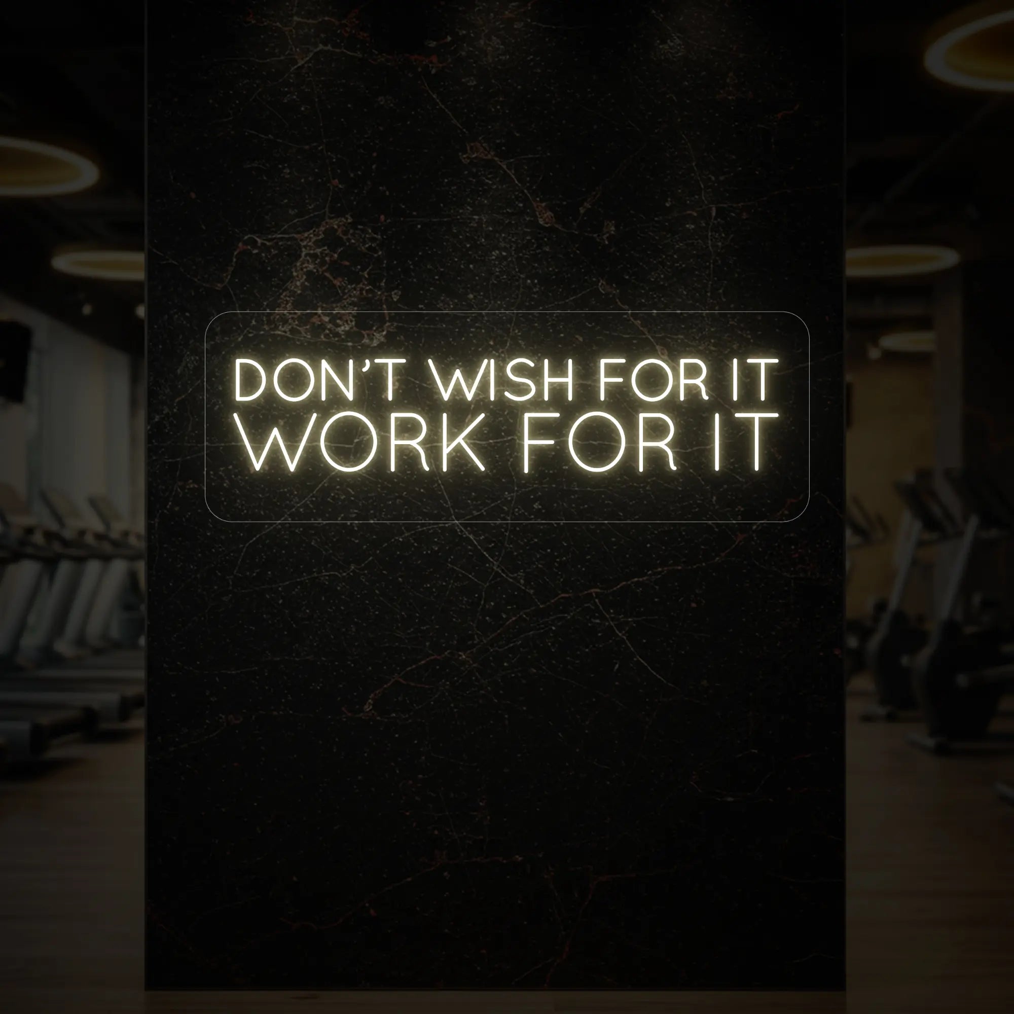 'Don’t Wish For It, Work For It' neon sign glowing in warm white against a styled interior wall.