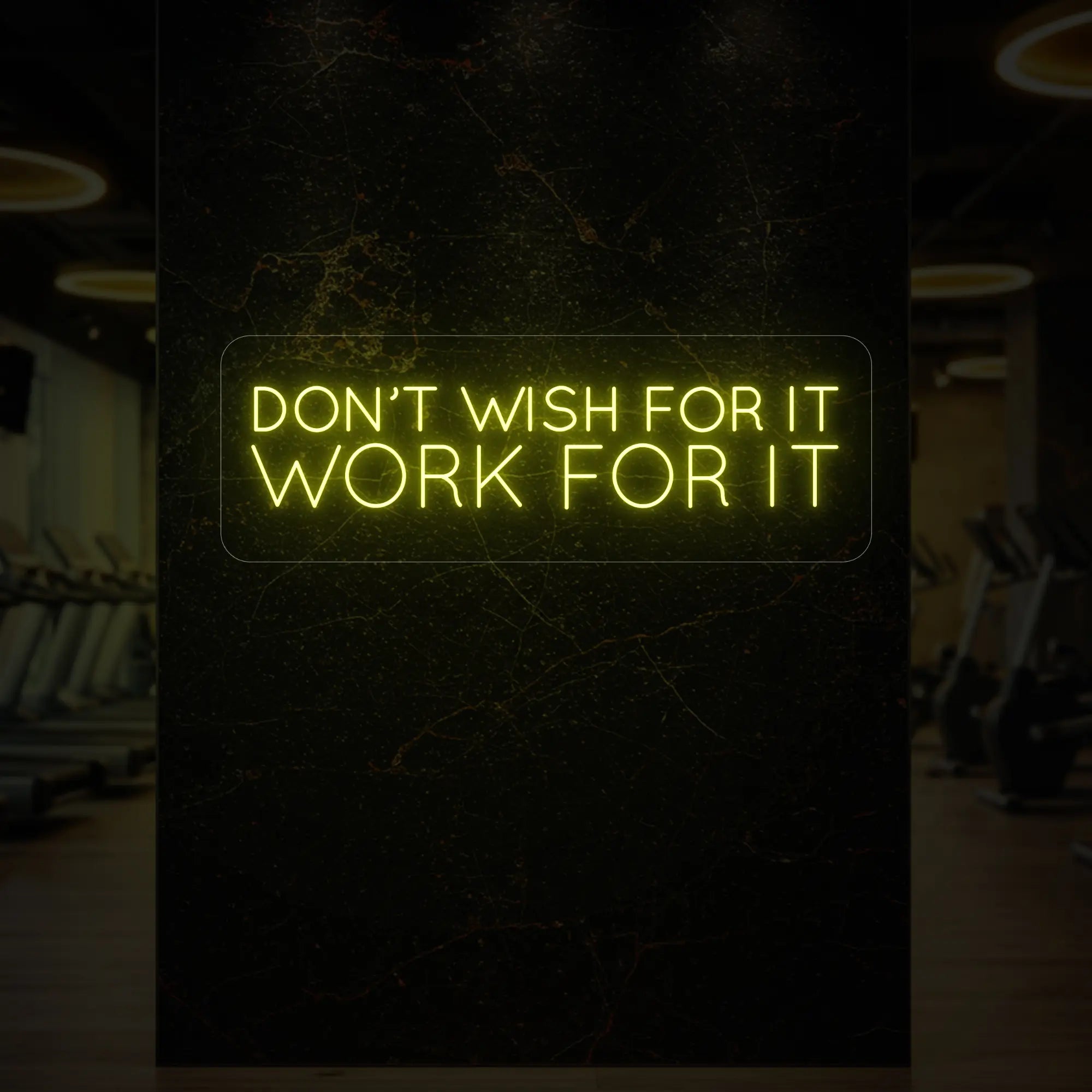 'Don’t Wish For It, Work For It' neon sign glowing in lemon yellow against a styled interior wall.