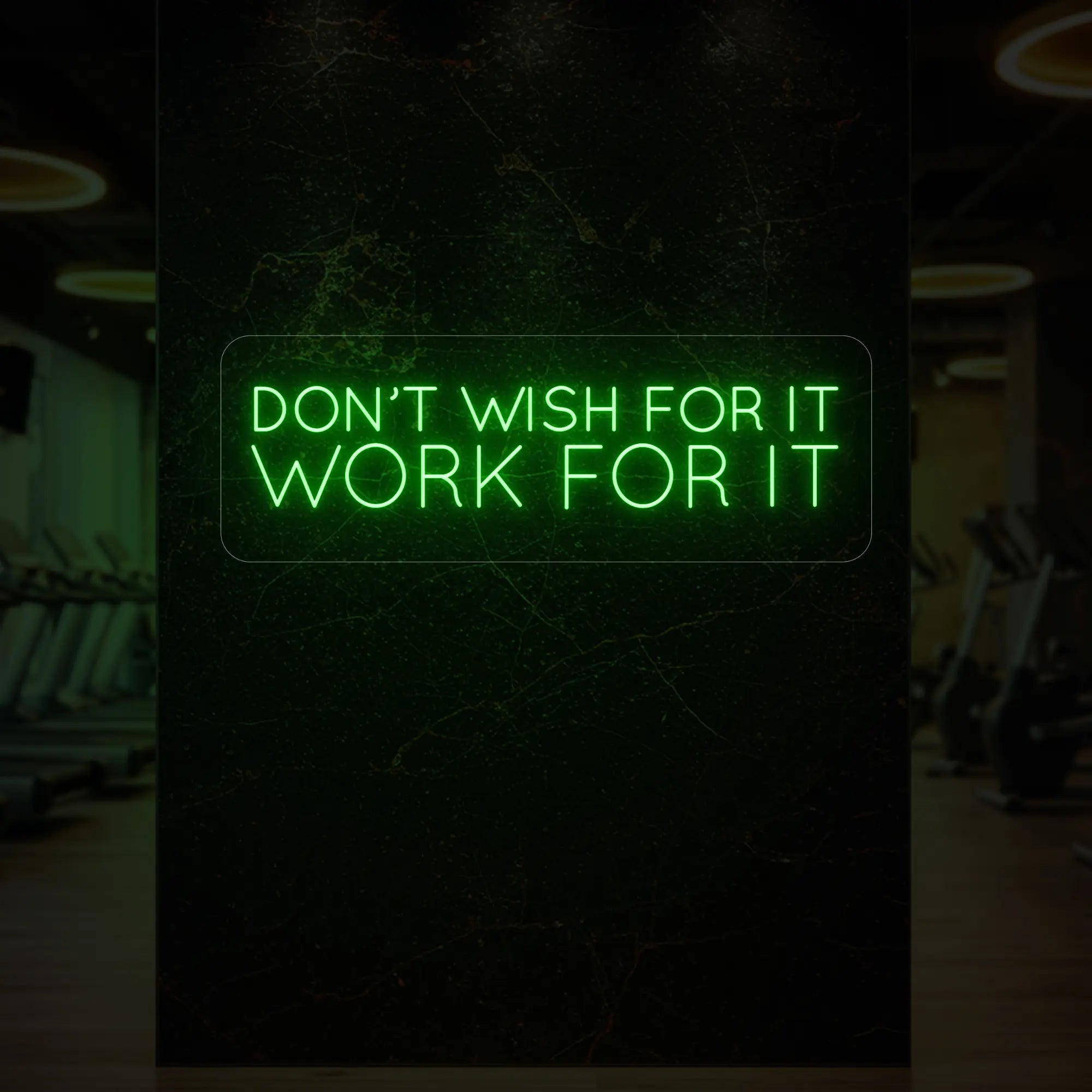 'Don’t Wish For It, Work For It' neon sign glowing in green against a styled interior wall.