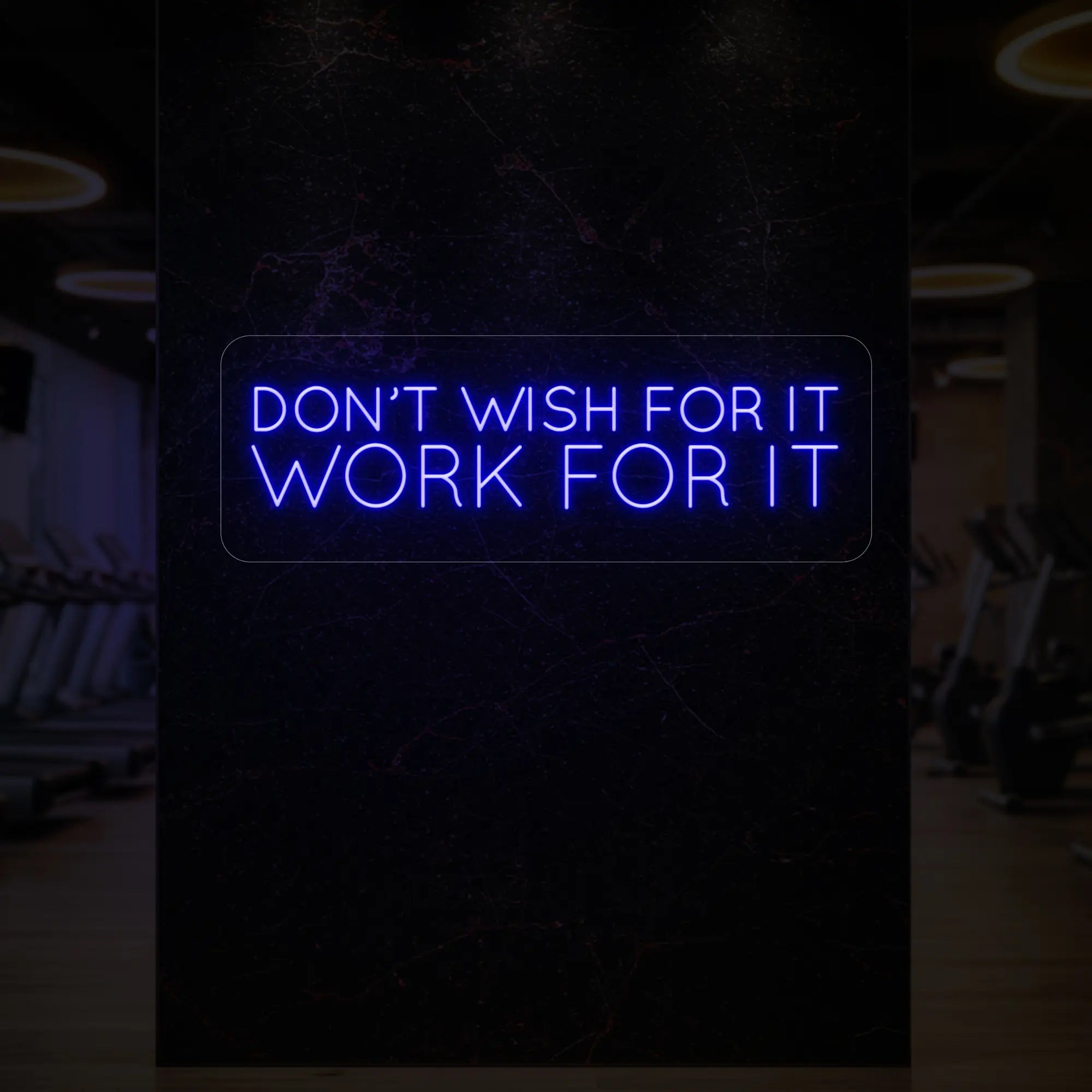 'Don’t Wish For It, Work For It' neon sign glowing in deep blue against a styled interior wall.