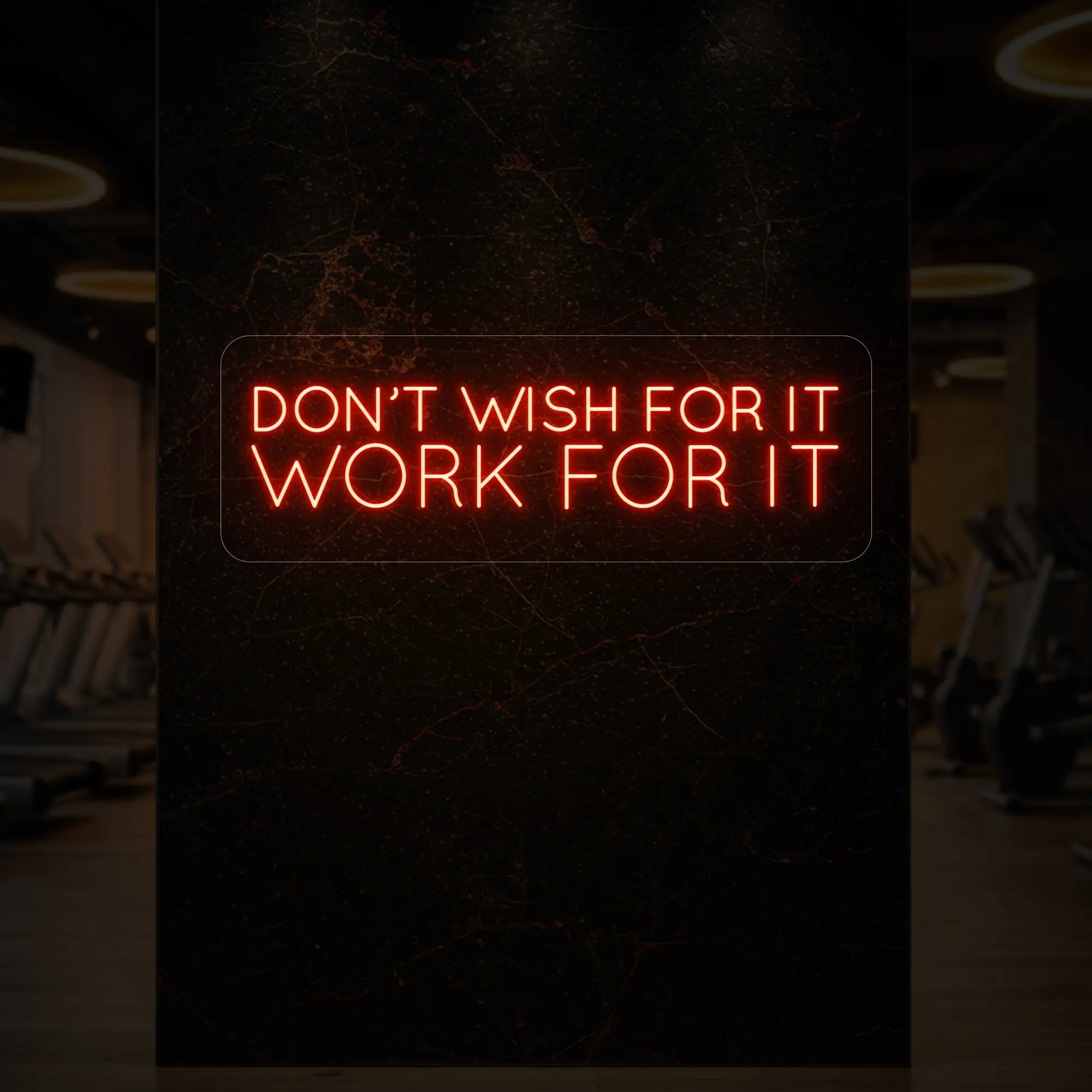 'Don’t Wish For It, Work For It' neon sign glowing in golden yellow against a styled interior wall.