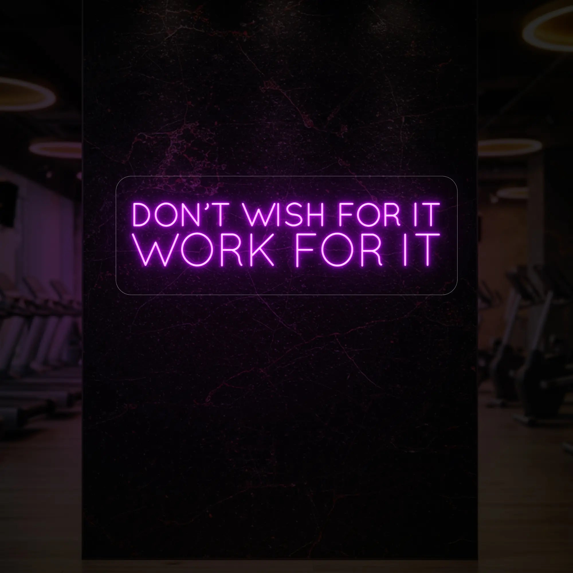 'Don’t Wish For It, Work For It' neon sign glowing in deep pink against a styled interior wall.