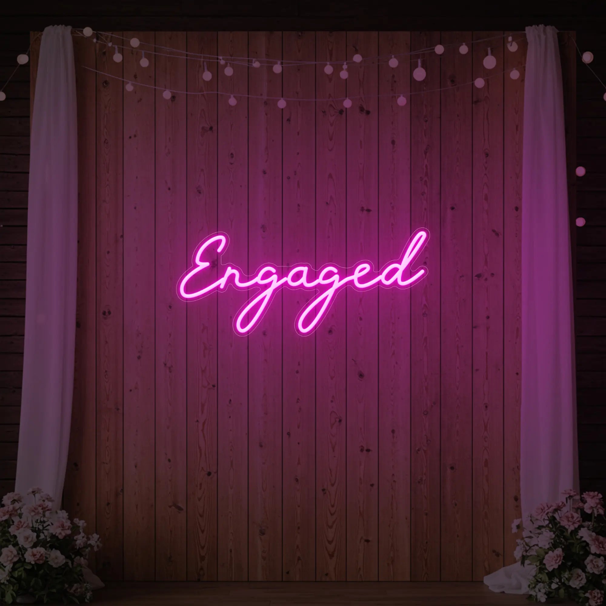 Photo of the 'Engaged' neon sign glowing in light pink against a styled interior wall.